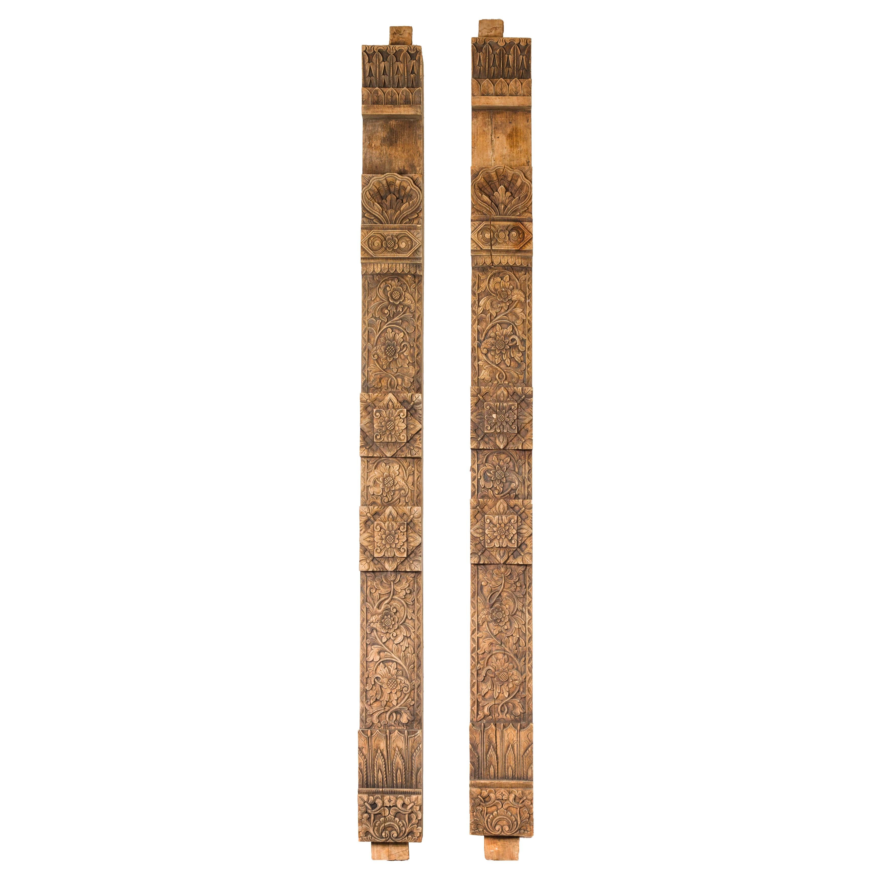 A pair of slender vertical architectural panels with hand-carved floral and foliage motifs. This exquisite pair of vintage slender vertical architectural panels captivates with their intricate hand-carved floral and foliage motifs. Standing tall and