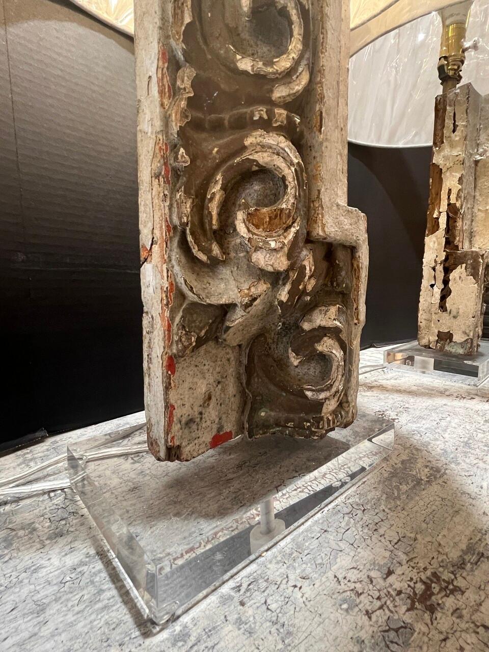 Experience the fusion of old-world charm and contemporary flair with this exquisite pair of lamps. Crafted from antique architectural fragments, they stand atop sleek lucite bases, marrying history with modernity. Each piece boasts new wiring,