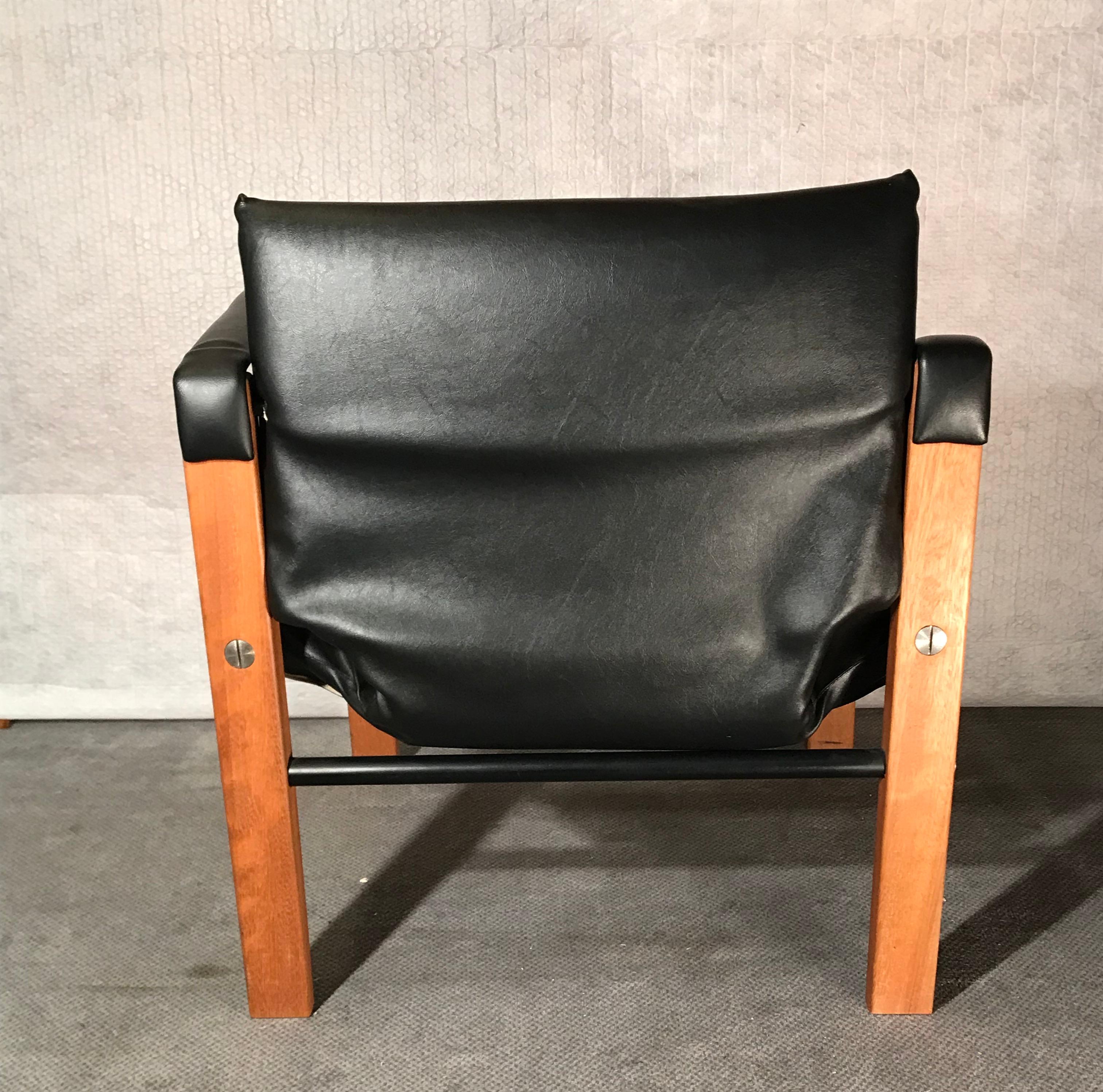 Stunning pair of safari chairs designed by Maurice Burke in Bath England, 1970s. 
These black safari chairs are upholstered in a black marine grade vegan leather and are accented with stainless steel rivets on a gorgeous teak frame. These safari
