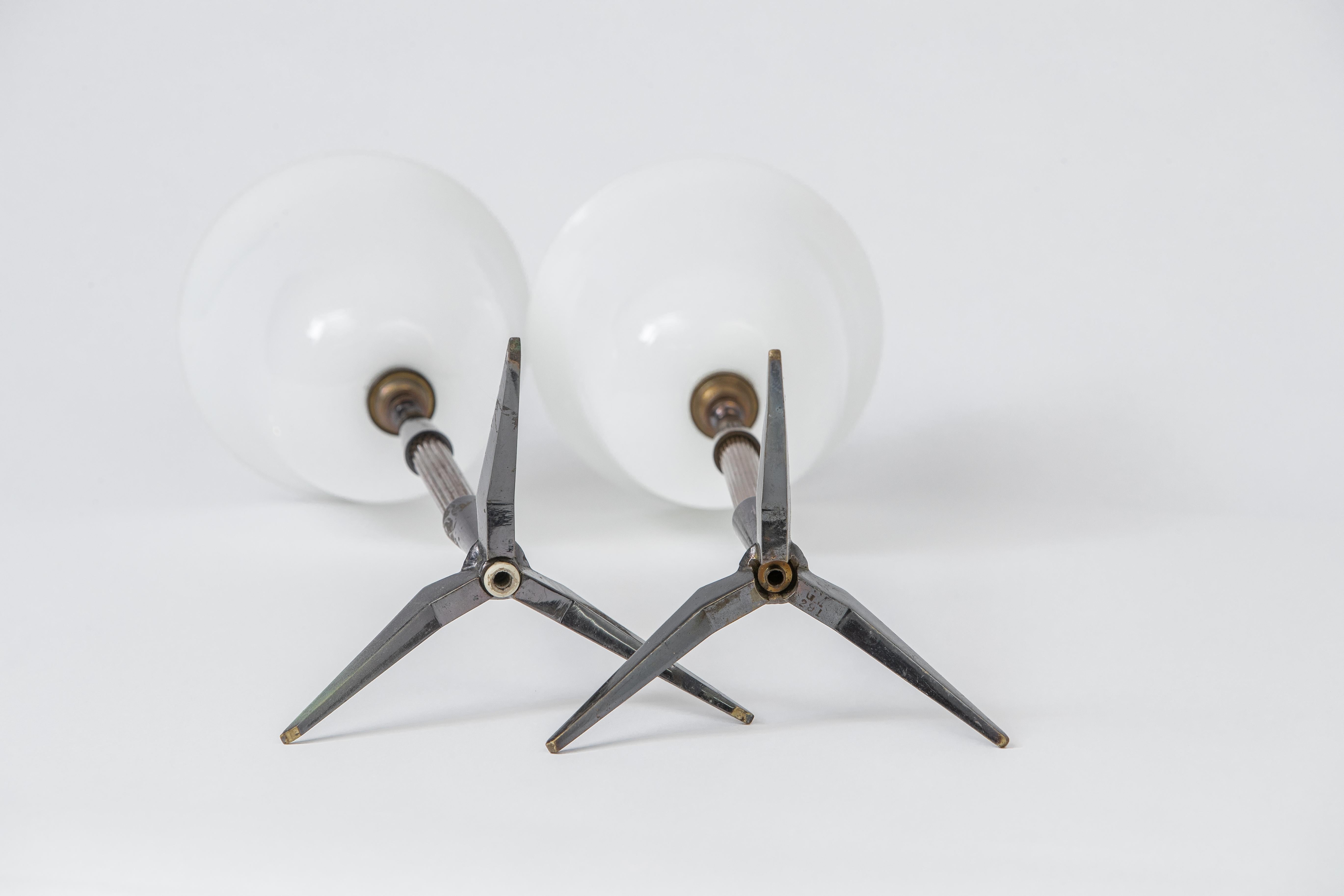 Elegant pair of tripod bronze table lamps by Arlus finished in a combination of gold and gunmetal patinas. Presented here with their original glass diffusers.