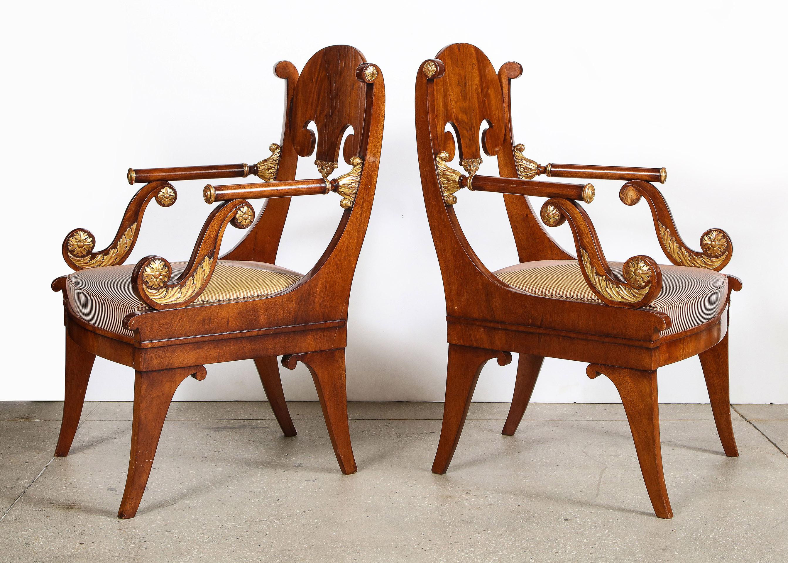 Pair of Russian neoclassical parcel-gilt mahogany armchairs

Each armchair made during the Empire period in Russia. The mahogany veneered frame with gilded details. With unusual tubular mahogany arms on 