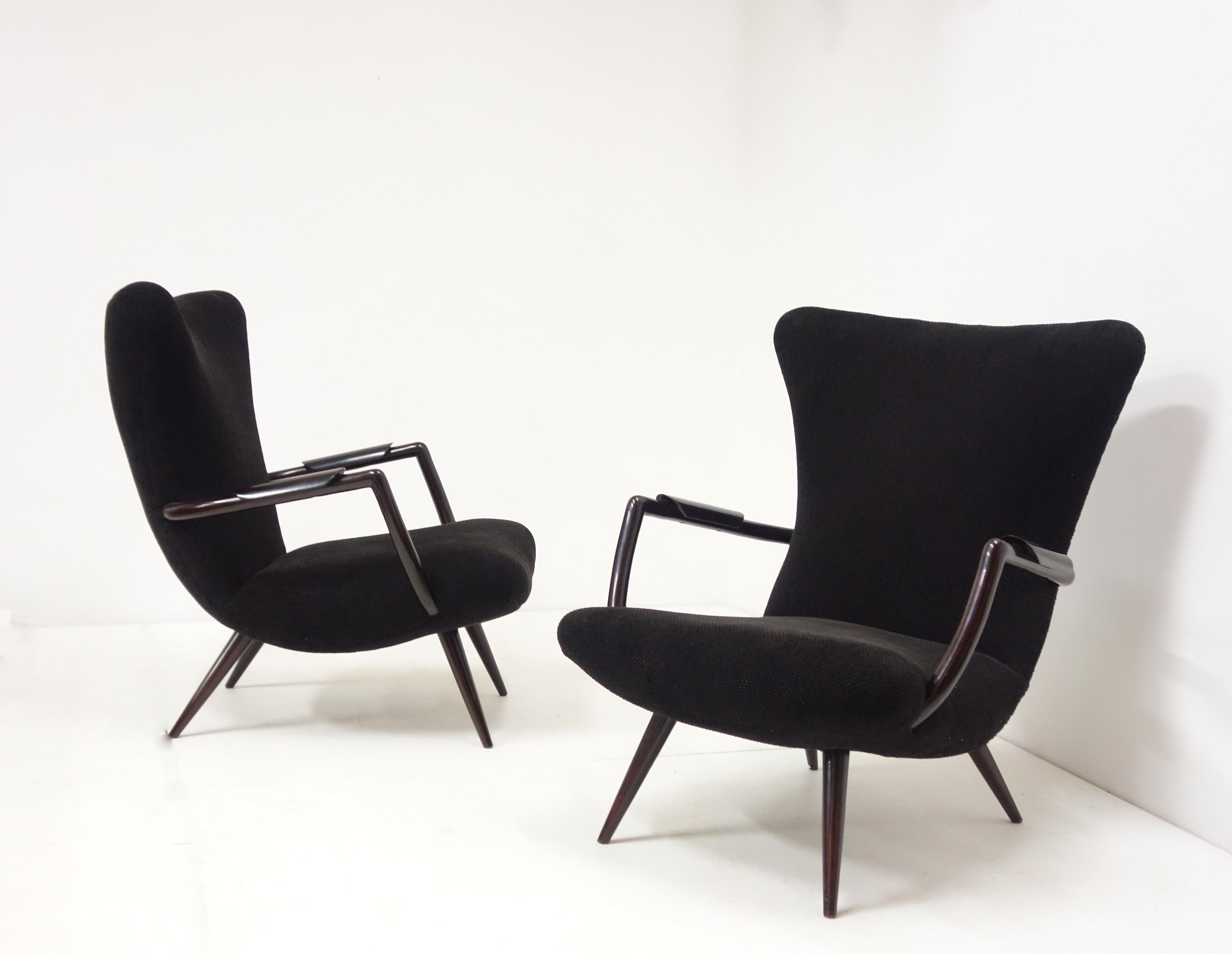 Pair of armchairs in blackened caviuna. The seat, as the curved and high back are upholstered with a knit dark fabric. The wood legs are slender and the armrests, also made of wood are curved with a wood cuff.
This elegant pair of armchairs is