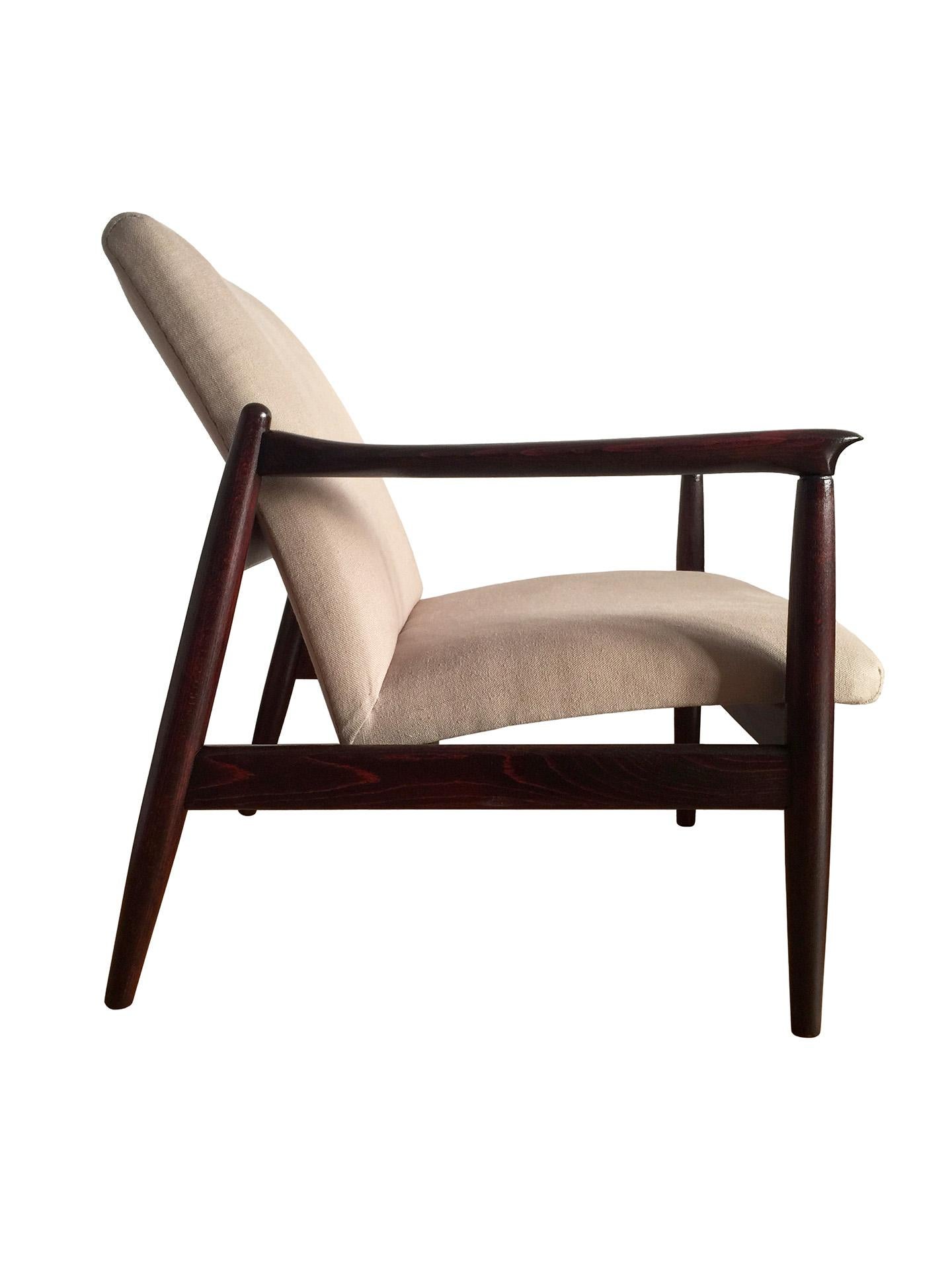 One of the icon of Polish midcentury design, model GFM-64 armchair, designed by Edmund Homa, has been manufactured by Goscinska Furniture Factory in Poland in the 1960s. The structure is made of solid beechwood in a warm palisander color, finished
