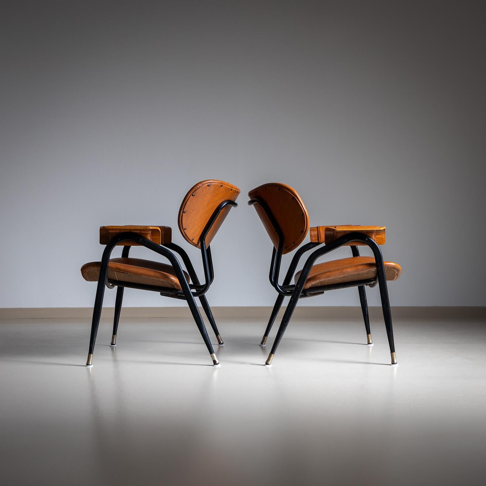 Paar Sessel mit schwarzen Eisenfüßen und ovalen Rückenlehnen und Sitzen mit braunen Kunstlederbezügen. Die Sitze und Rückenlehnen sind rautenförmig verziert. 