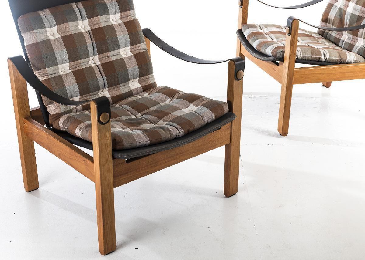 Mid Century designer pair of armchairs by Hans Ehrlin for Nordiska Kompaniet. Pair of rare, high-back safari model chairs from the mid-60s, designed by Hans Ehrlin for Nordiska Kompaniet. Armrest in leather, seat and back in black canvas with