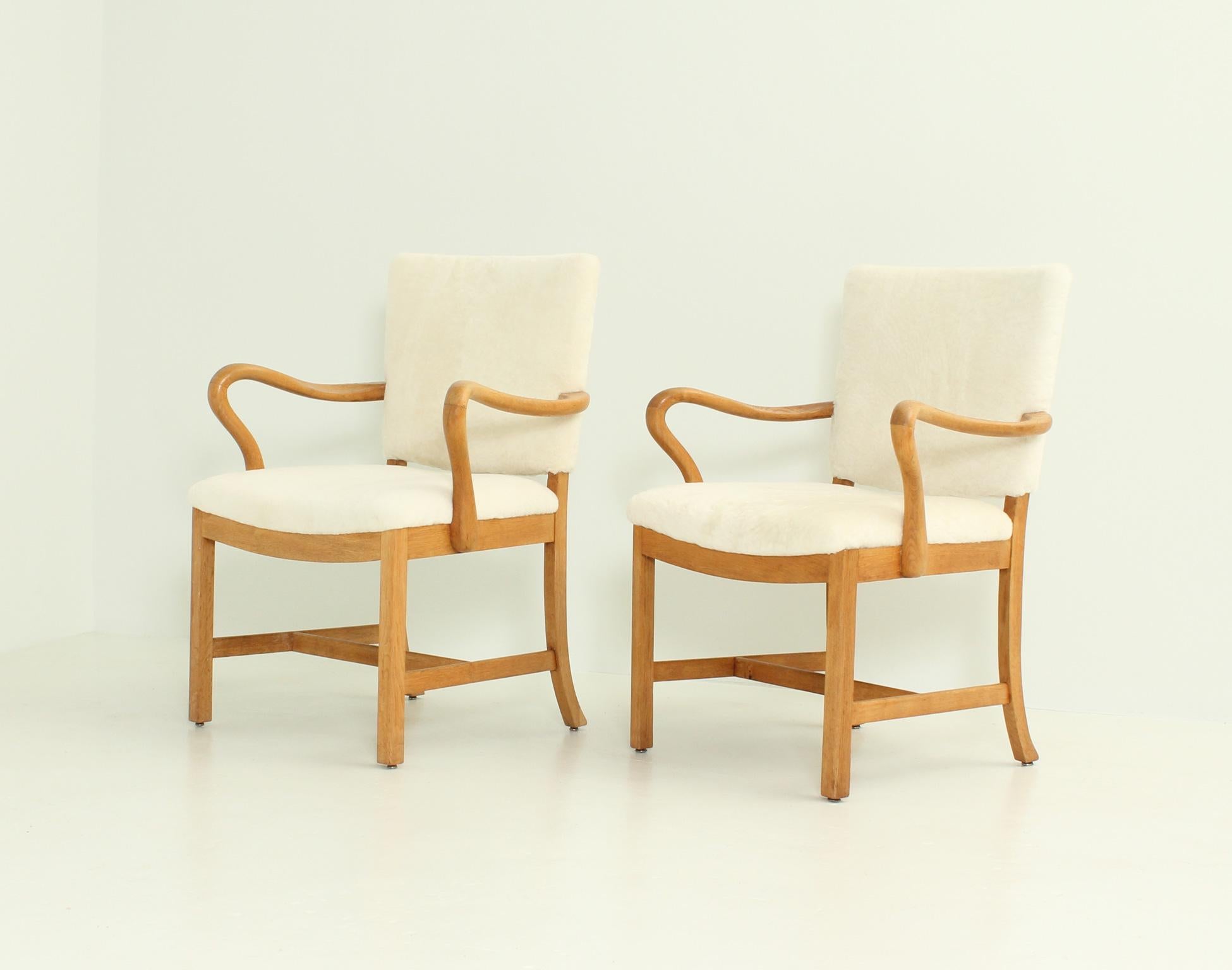 Pair of armchairs designed in 1930's by danish cabinetmaker Jacob Kjaer, Denmark. Interesting hand carver work in solid oak wood and re-upholstered with new sheepskin.
