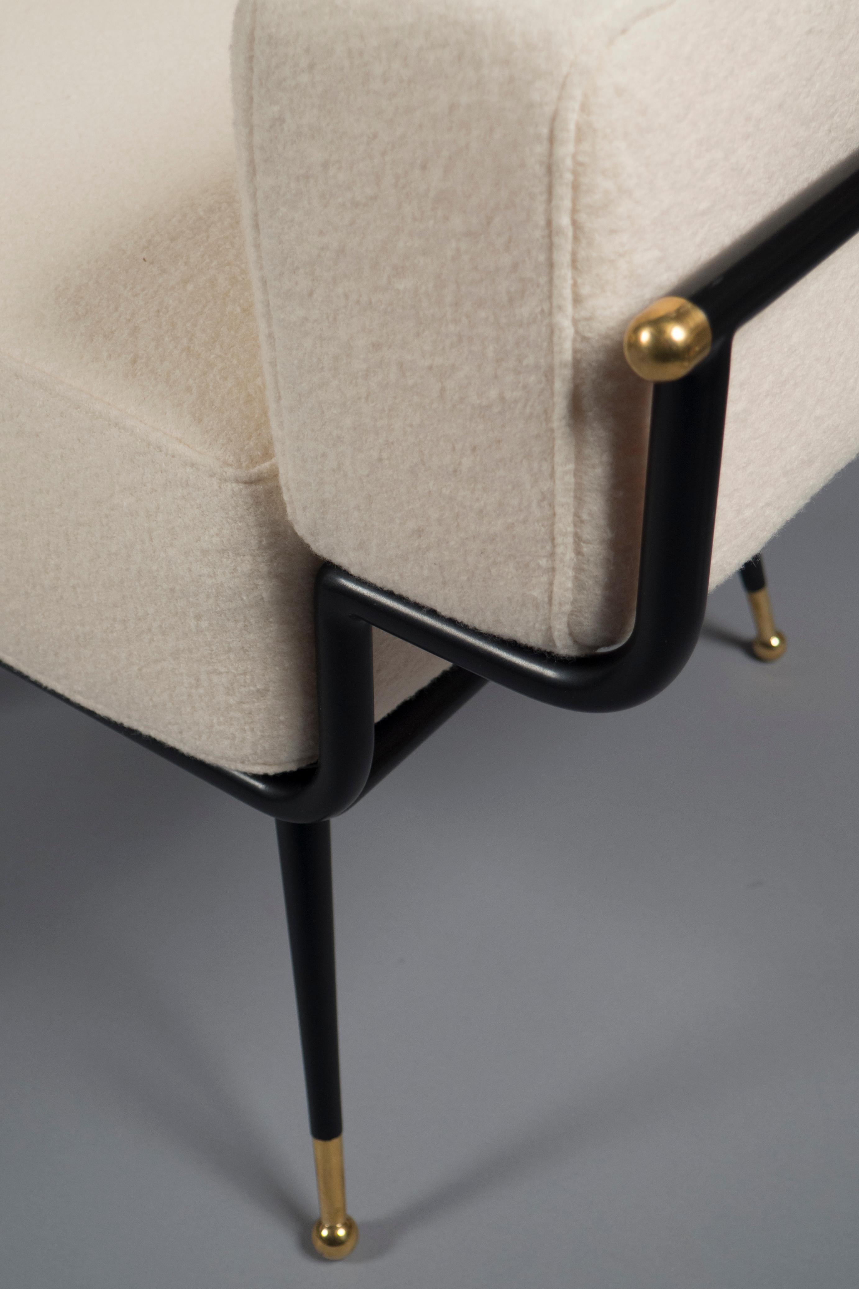 Black metal frames with polished brass details holding a formed foam seat, back and armrests. Splayed legs ending in round brass sabots complete the look.

Measures: Height 30.5”, width 33.5”, depth 30” 
Arm height 23.5”, seat height 16”. 
     