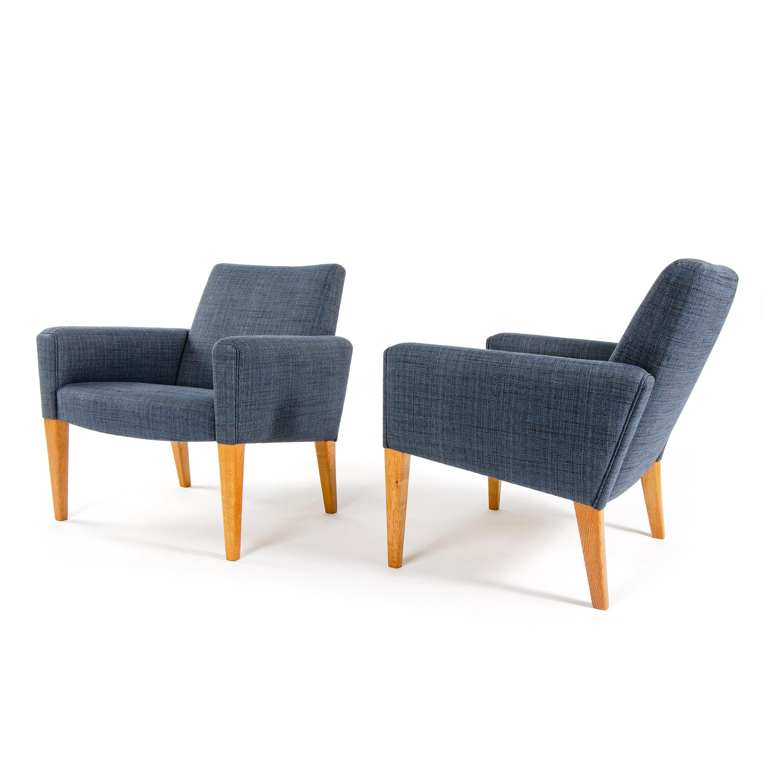 A pair of lounge chairs, newly upholstered in a dark blue, cotton and linen weave, on top of tapered wood legs. Designed by Hans Wegner, made by AP Stolen in Denmark, circa 1950s.