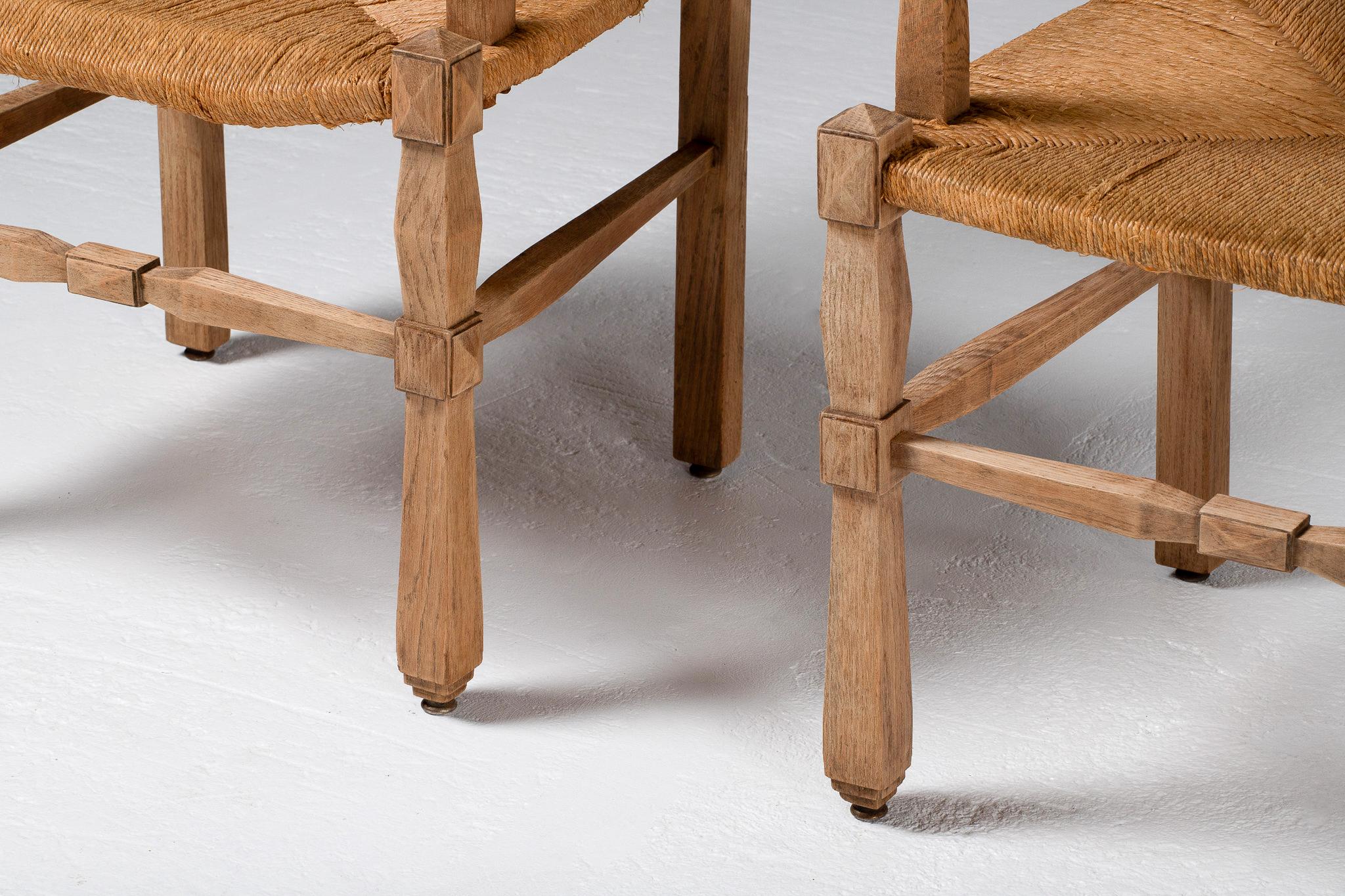 With their upright silhouettes and pronounced finials, these armchairs assert a kind of rustic nobility—firm in their bearing, yet softened by the woven tactility of rush. The back and seat unfold in a chevron weave, tightly drawn and warm to the