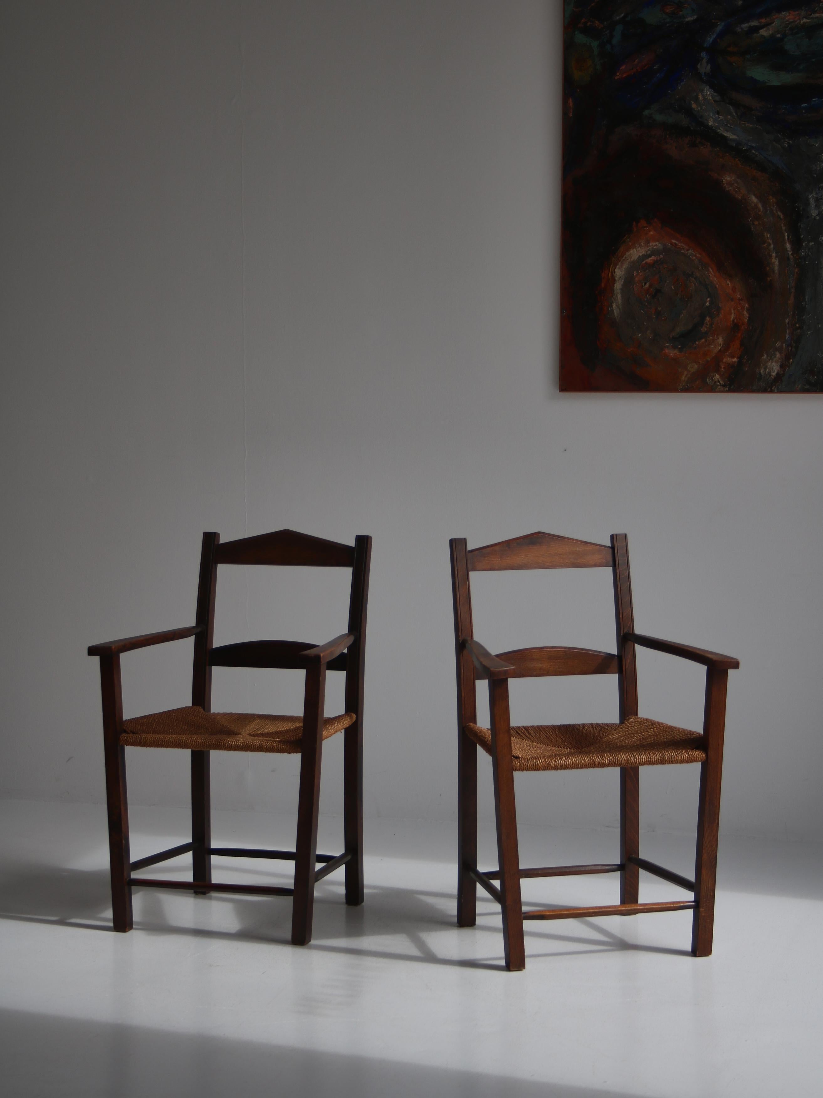 Charming pair of armchairs in dark stained pinewood with seats of woven seagrass. The chairs are made in Denmark in the 1930-40s and have never been refinished. The design is simplistic yet elegant and the patina is just perfect. In the style of