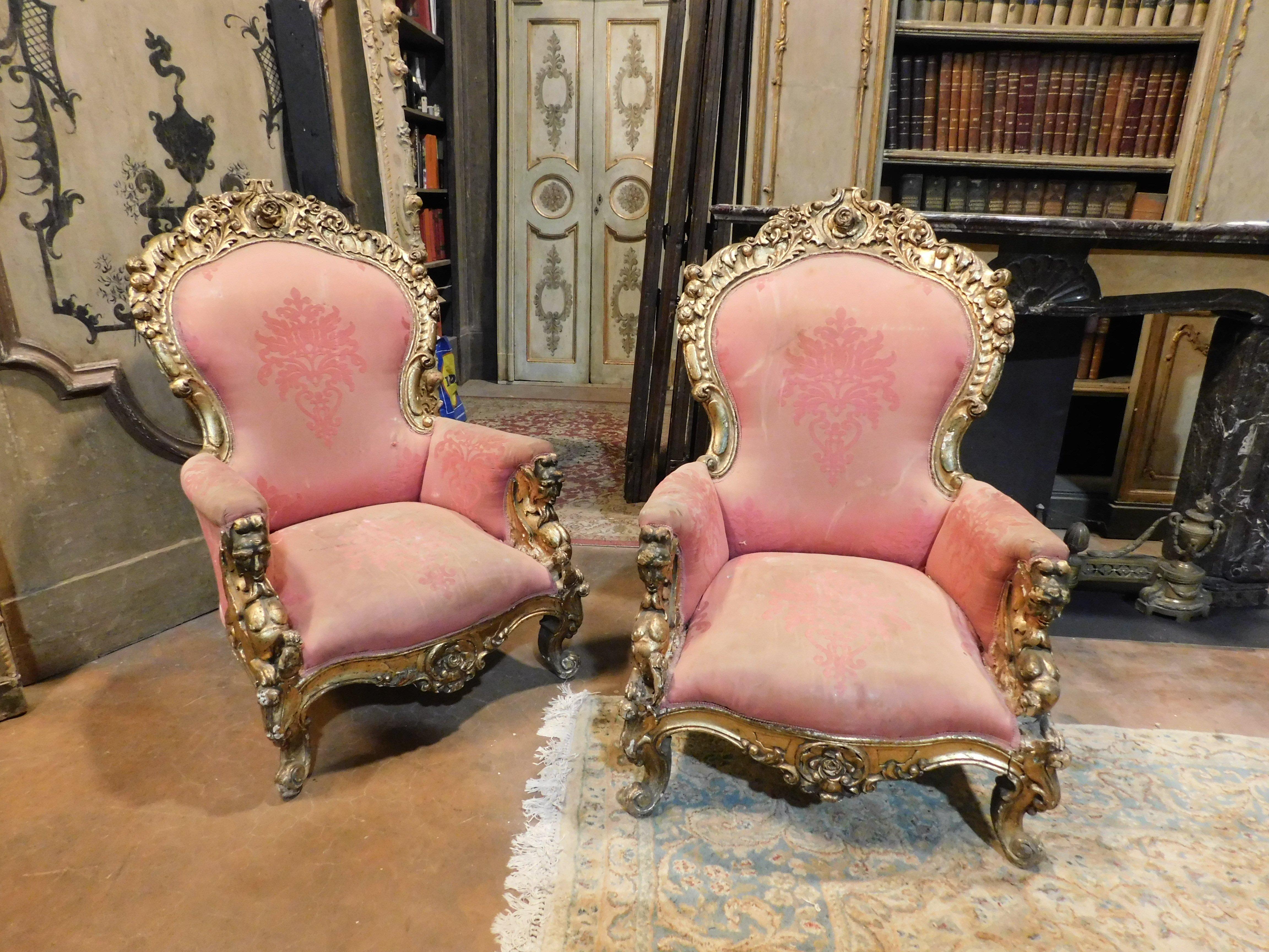 Pareja de sillones de madera maciza, dorada y ricamente tallada con decoraciones frondosas y florales. Tiene una elegante tela roja en buen estado, reposabrazos acolchados y una escultura de centauros sosteniendo un escudo. Precioso y muy bello,