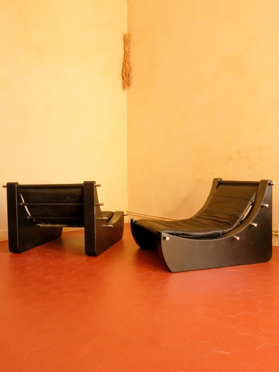 Paire de fauteuils en bois laqué, métal chromé et cuir noir rembourré, fabrication française, vers 1970, 59 x 85 x 91 cm. 
 
Cette paire de fauteuils à l'allure imposante est composée de formes géométriques dessinées sur différentes surfaces,