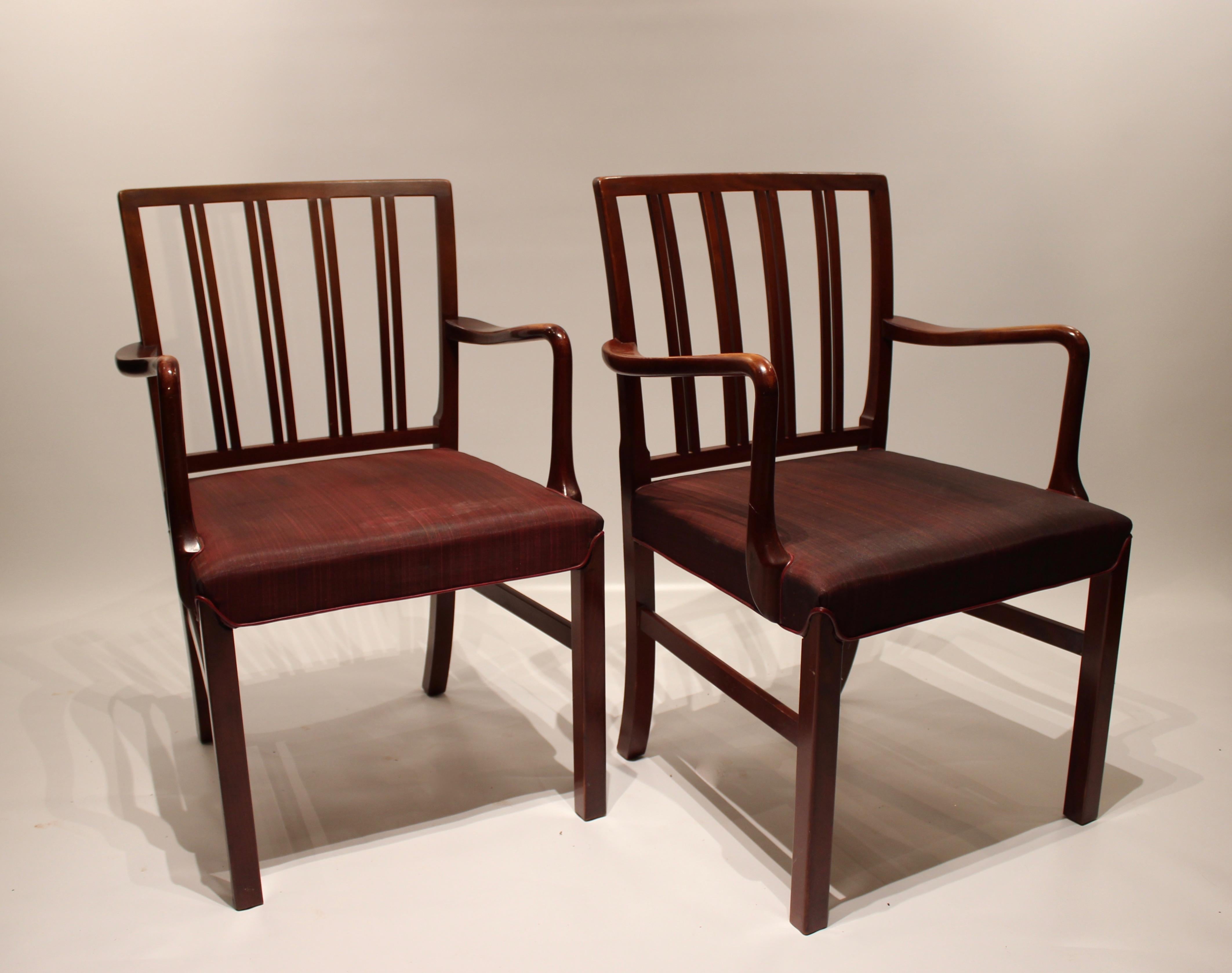 Ces fauteuils dégagent une élégance et une sophistication intemporelles, avec leur construction en bois d'acajou et leur revêtement en tissu rouge. Ils ont été conçus par l'emblématique designer de meubles danois Fritz Hansen dans les années 1930 et