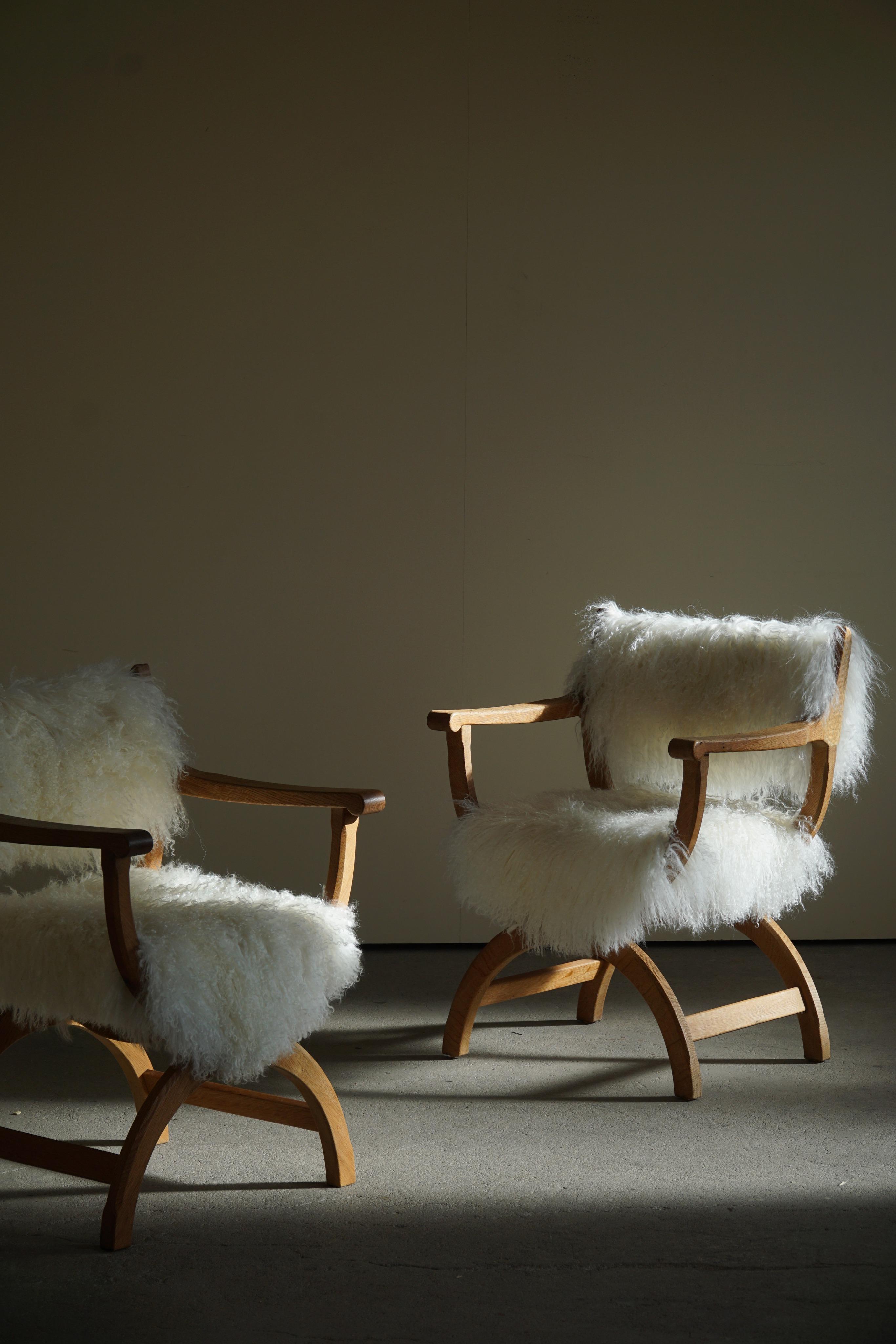 A lovely pair of armchairs / desk chairs in solid oak, professionally reupholstered in long haired lambswool from Tibet. Designed by Henning (Henry) Kjaernulf for EG Kvalitetsmøbel, Denmark 1960s. Model 
