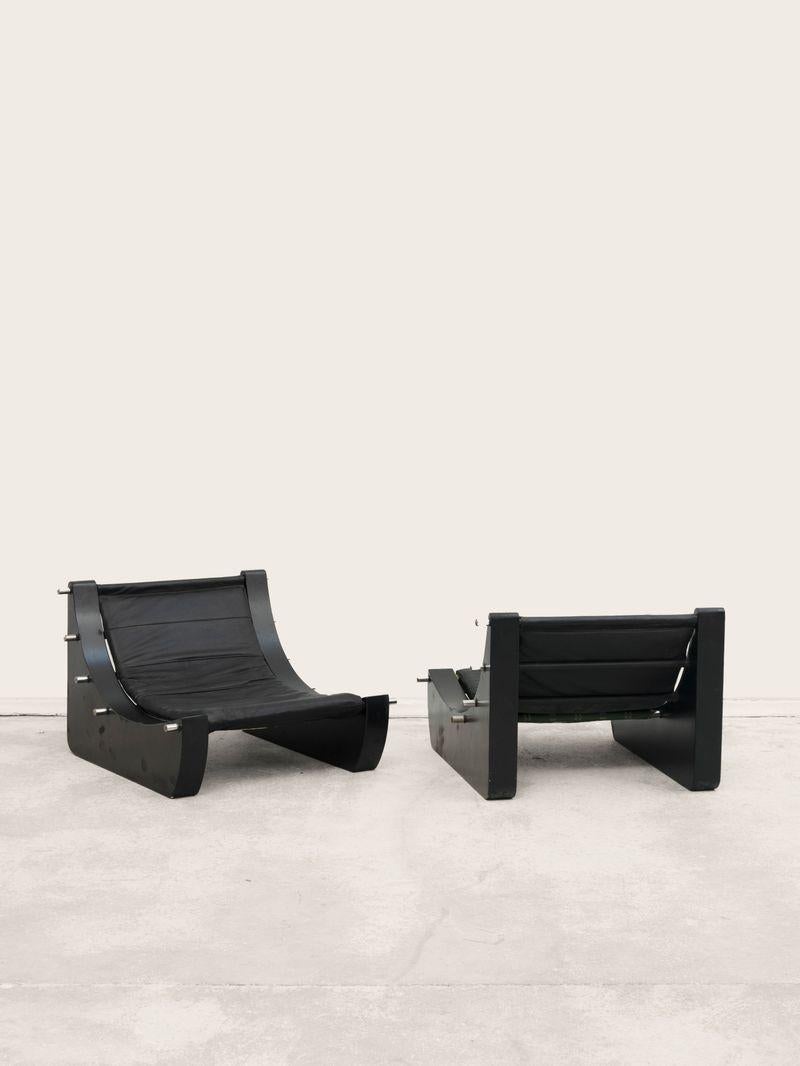 Pair of armchairs in lacquered wood, chromed metal and upholstered black leather, French manufacture, circa 1970, 59 x 85 x 91 cm. 
 
This pair of armchairs has an imposing appearance and is composed of geometric shapes drawn on different