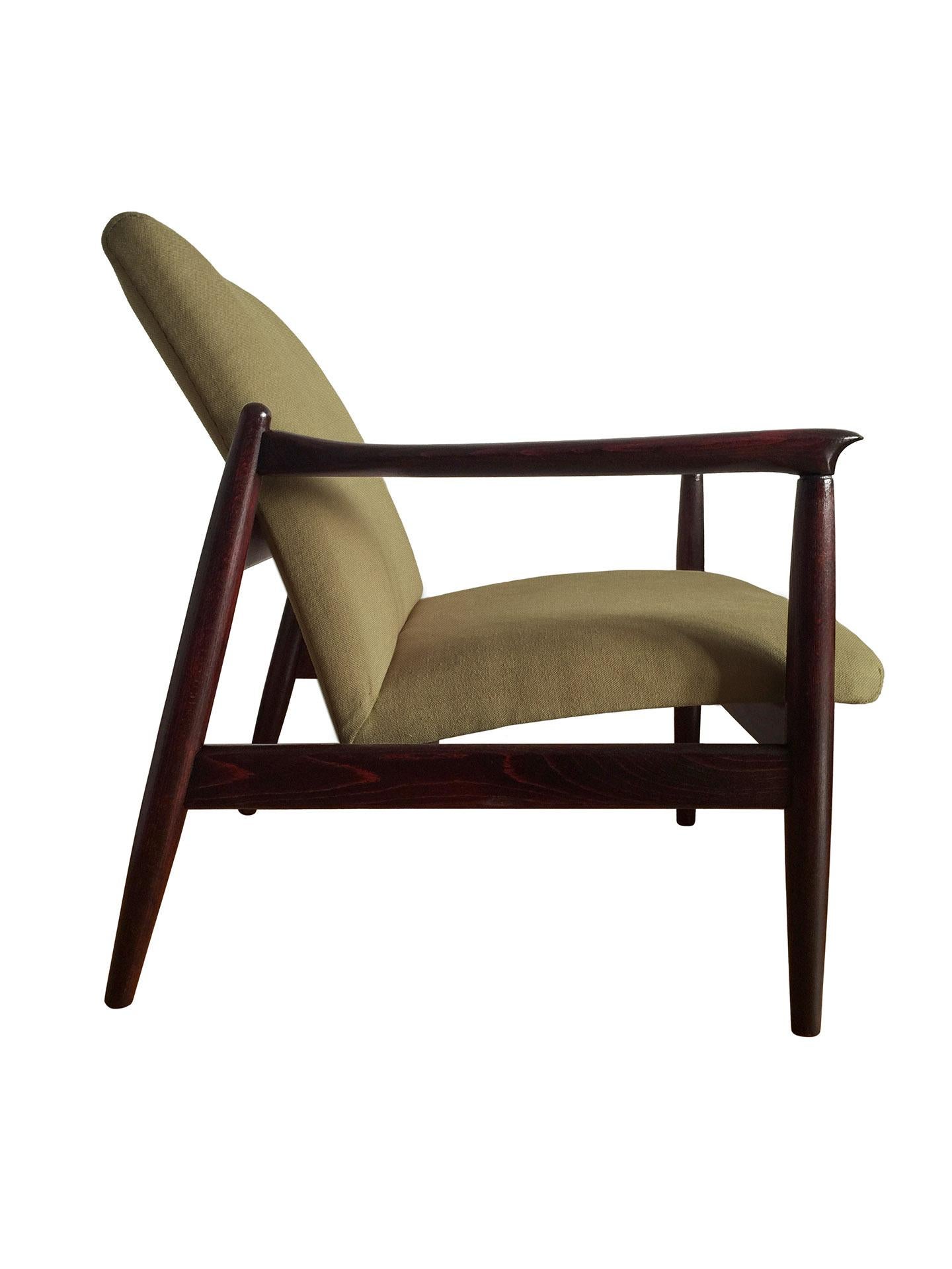One of the icon of Polish midcentury design, model GFM-64 armchair, designed by Edmund Homa, has been manufactured by Goscinska Furniture factory in Poland in the 1960s. The structure is made of solid beechwood in a warm palisander color, finished