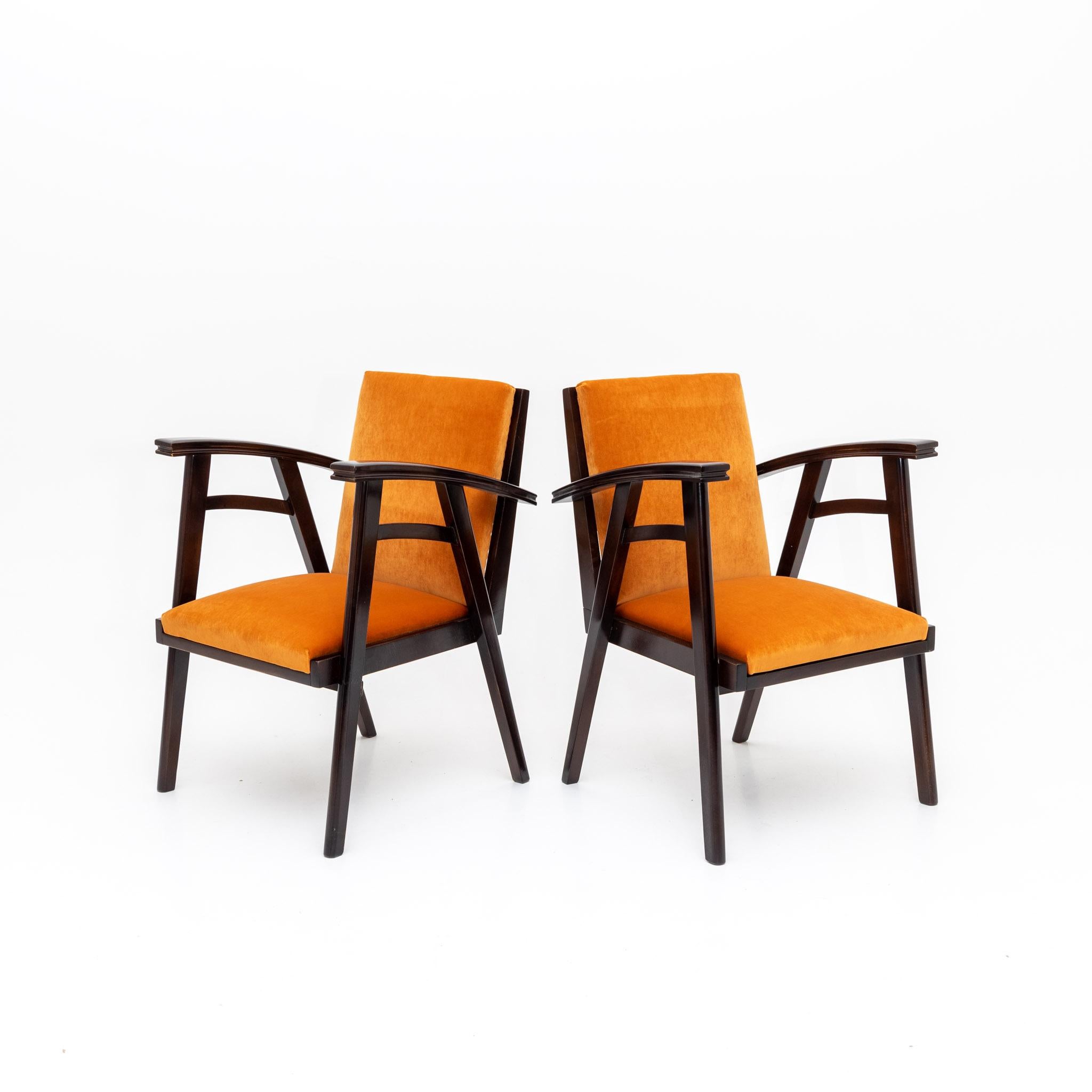 Pair of armchairs with dark stained wooden frames and upholstered seats. The arm chairs have been reupholstered in an orange velvet fabric.