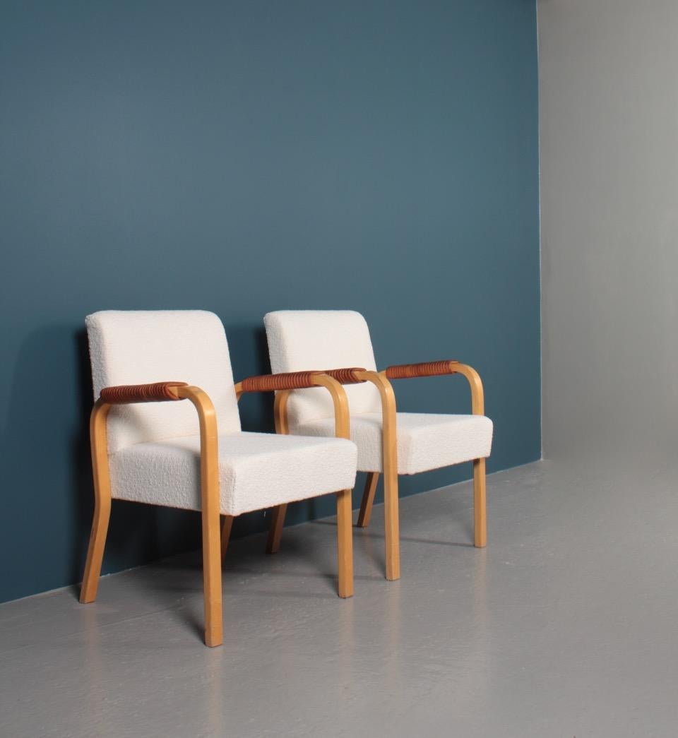 Pair of armchairs with bouclé fabric and patinated leather arms. Designed by Alvar Aalto in 1947 for Artek. Great condition.