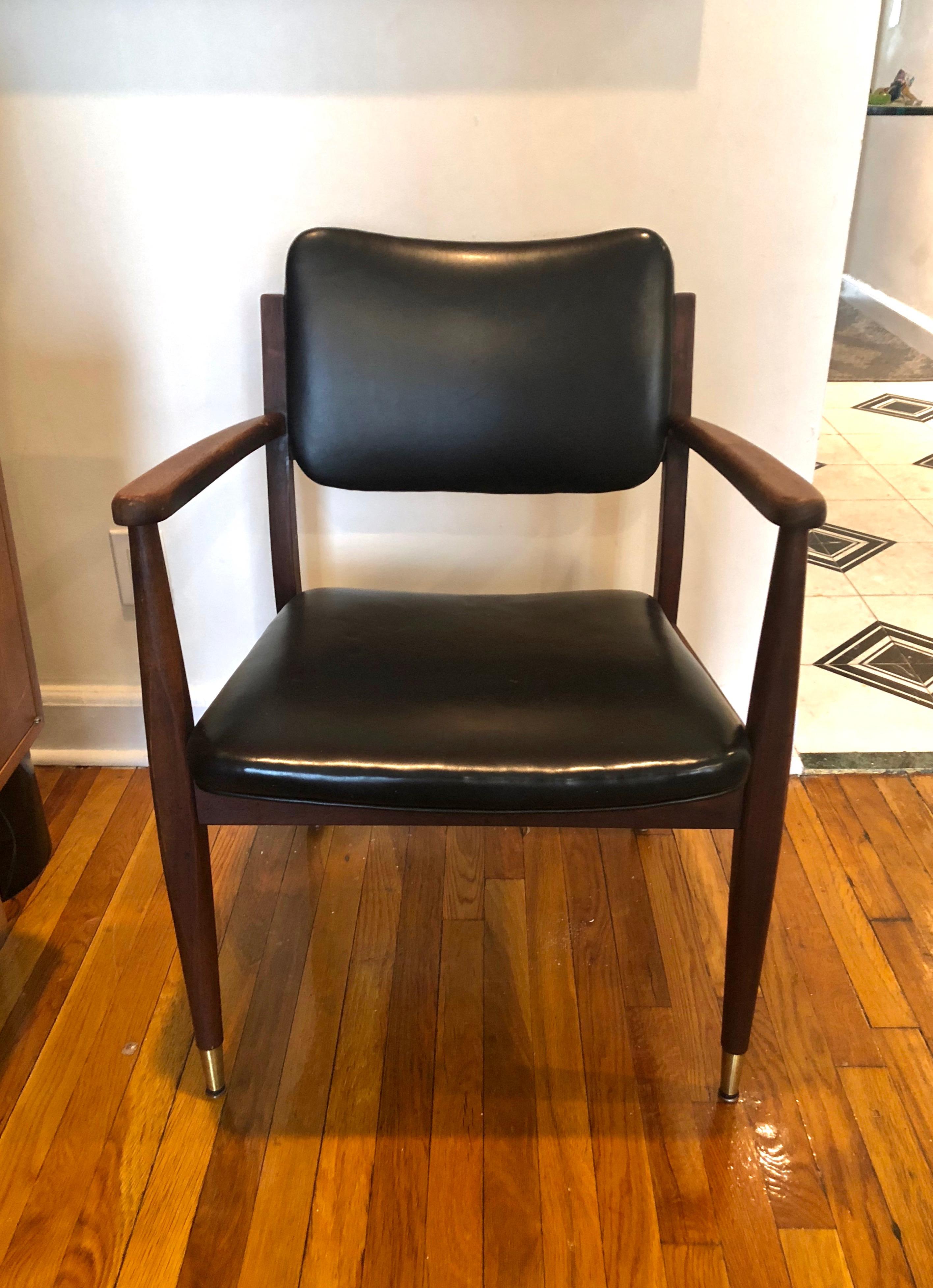 Pair of wooden framed lounge or desk armchairs with black leatherette cushions, brass sabots on the front tapering legs, and curved arms. Arm height is 26.75 inches.
