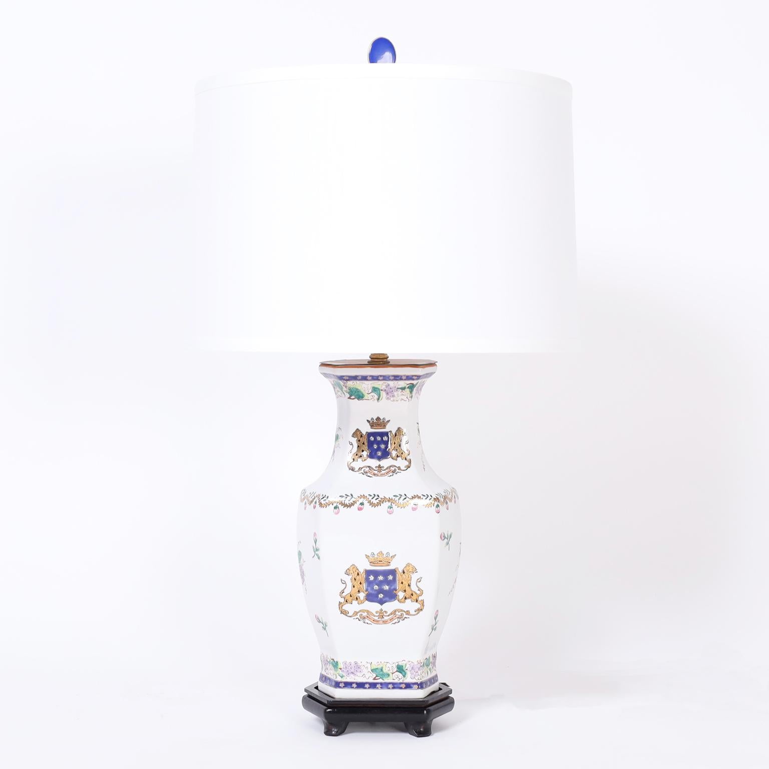 Pair of French porcelain table lamps with antique vases now lamps having classic form and armorial motifs with lions holding shields under a crown. Presented on Asian style wood bases.