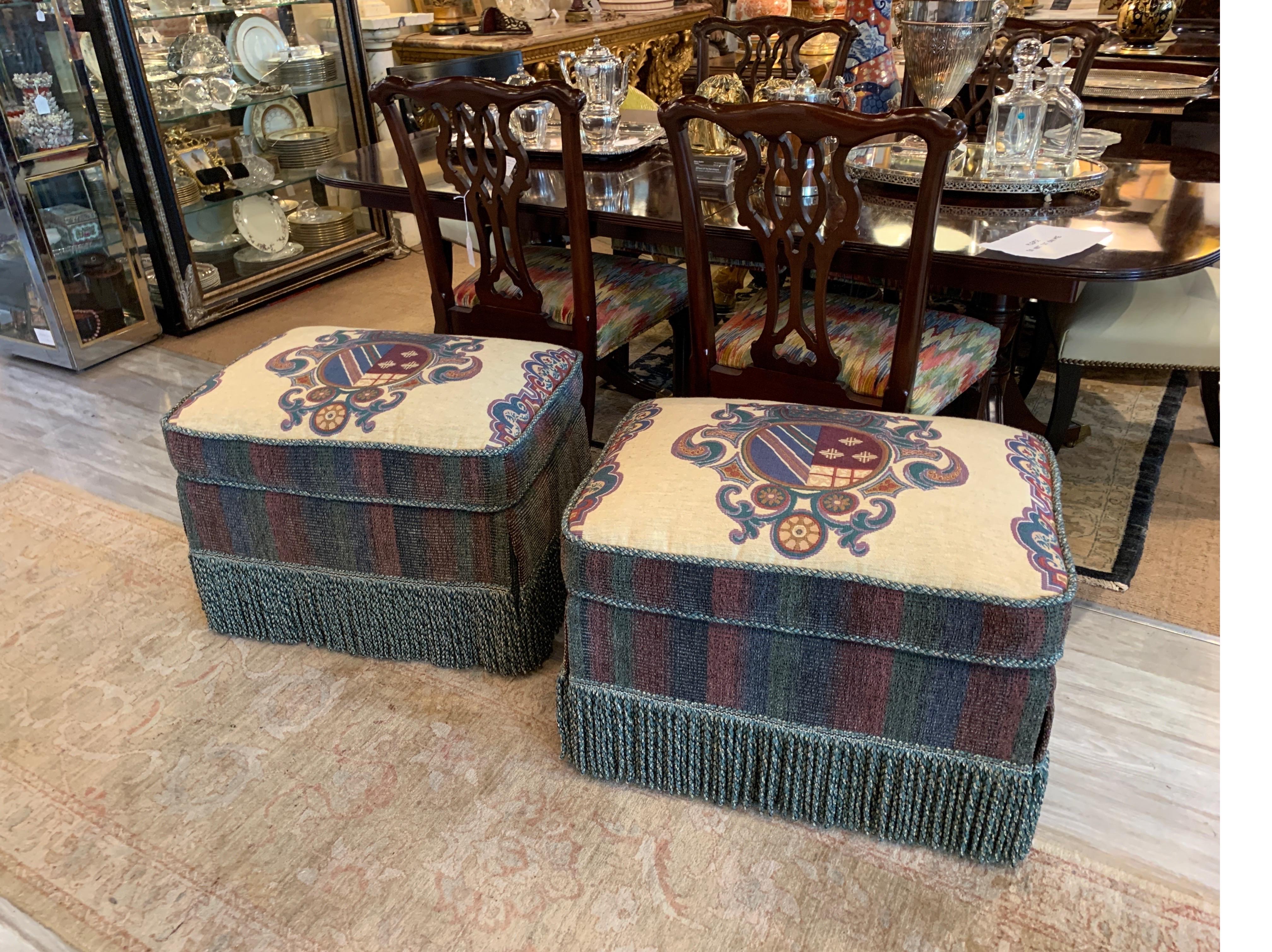 Pair of Armorial upholstered ottomans with Belgium woven tapestry armorial cushions with blue and red chenille sides, with lavish bouillon fringe skirt. Nice height of seat
Measures: 28