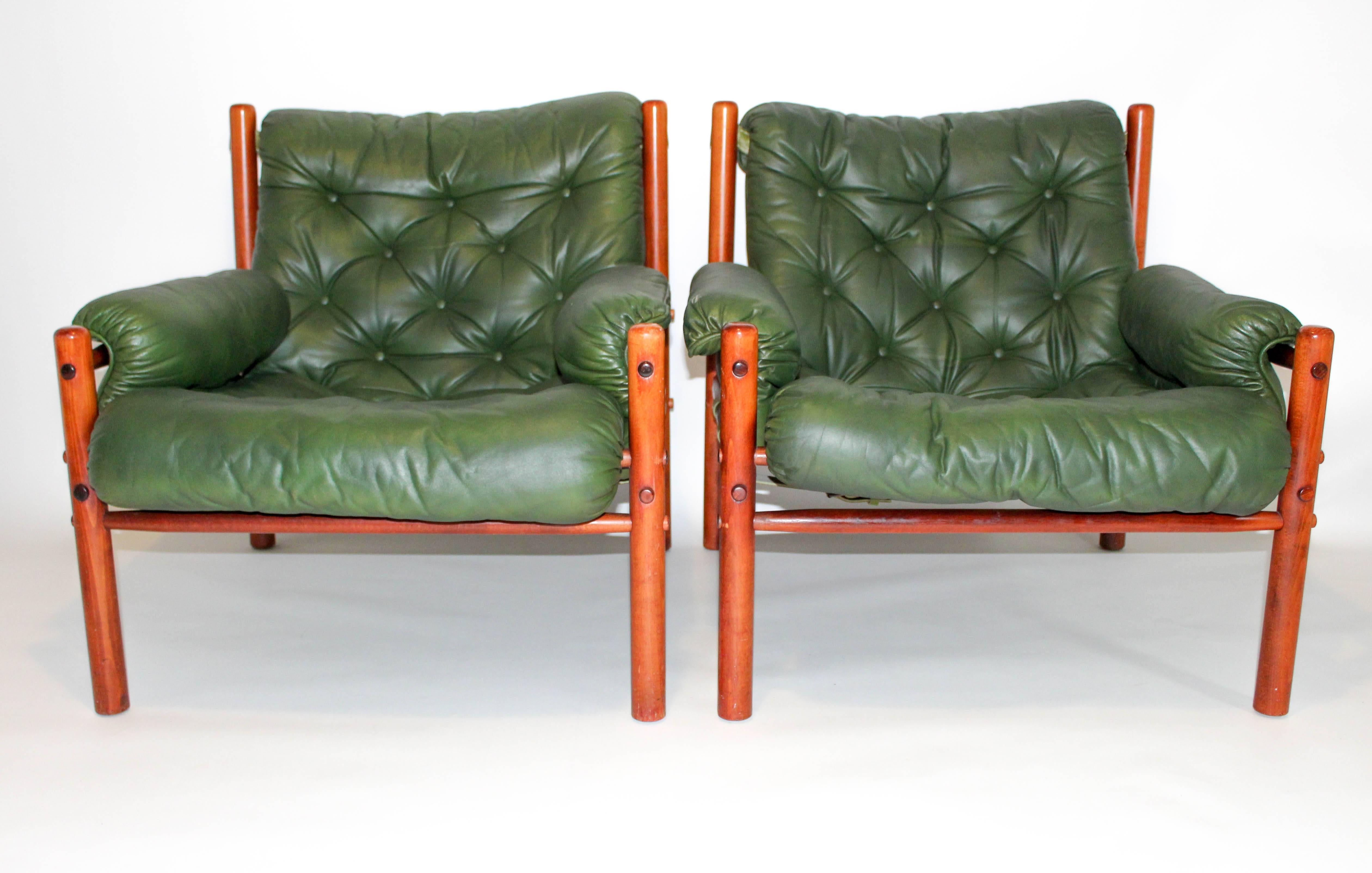 A pair of Arne Norell chairs in green leather, produced by Norell AB. These chairs are in very good vintage condition with signs of usage consistent with age. This is a rare model from this very popular Swedish designer that combines great design