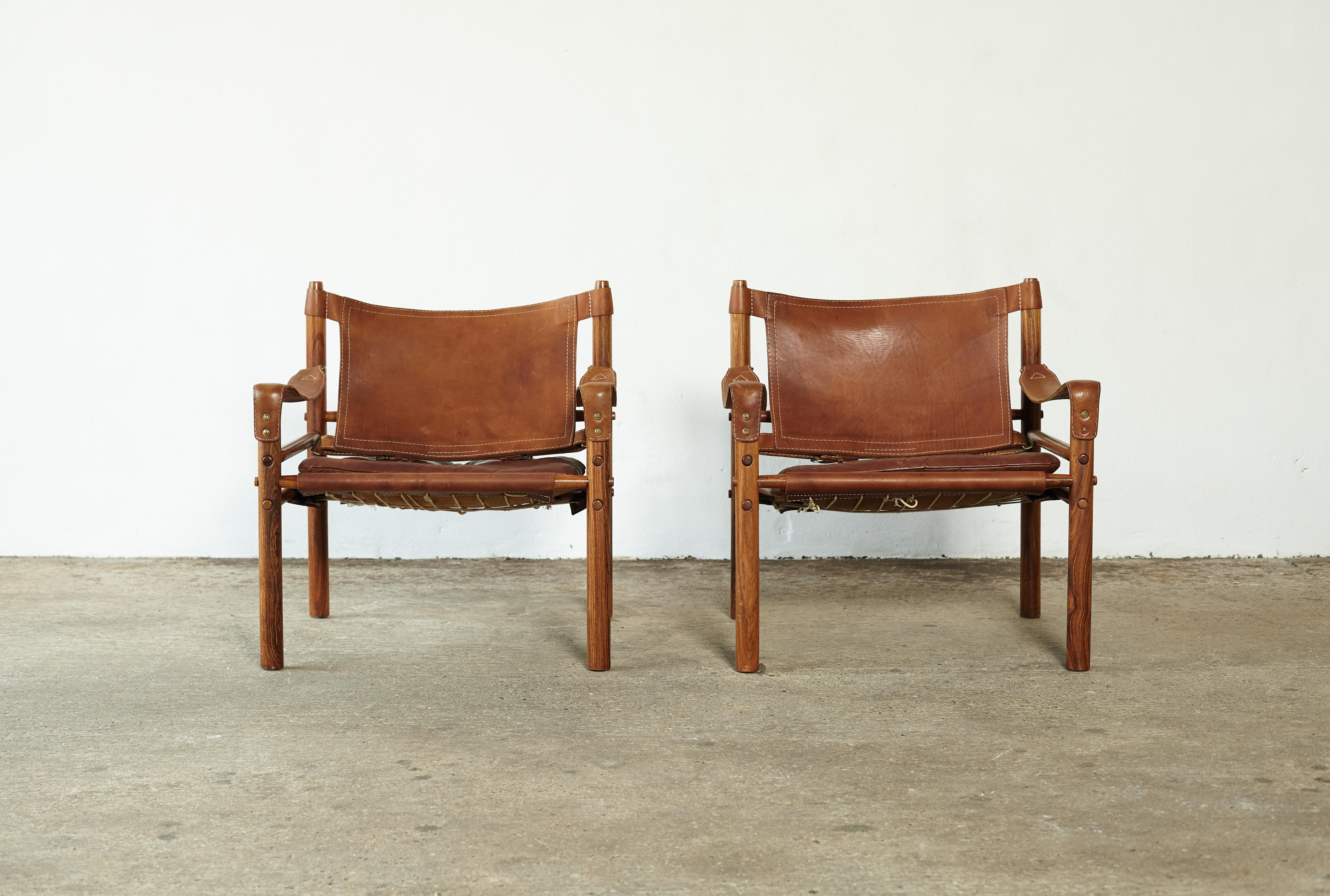 A super pair of authentic vintage Arne Norell safari sirocco chairs in rosewood and patinated brown leather. Made by Norell Mobler in Sweden. Very good original condition. 

The chairs will need to be disassembled for shipping but were designed to