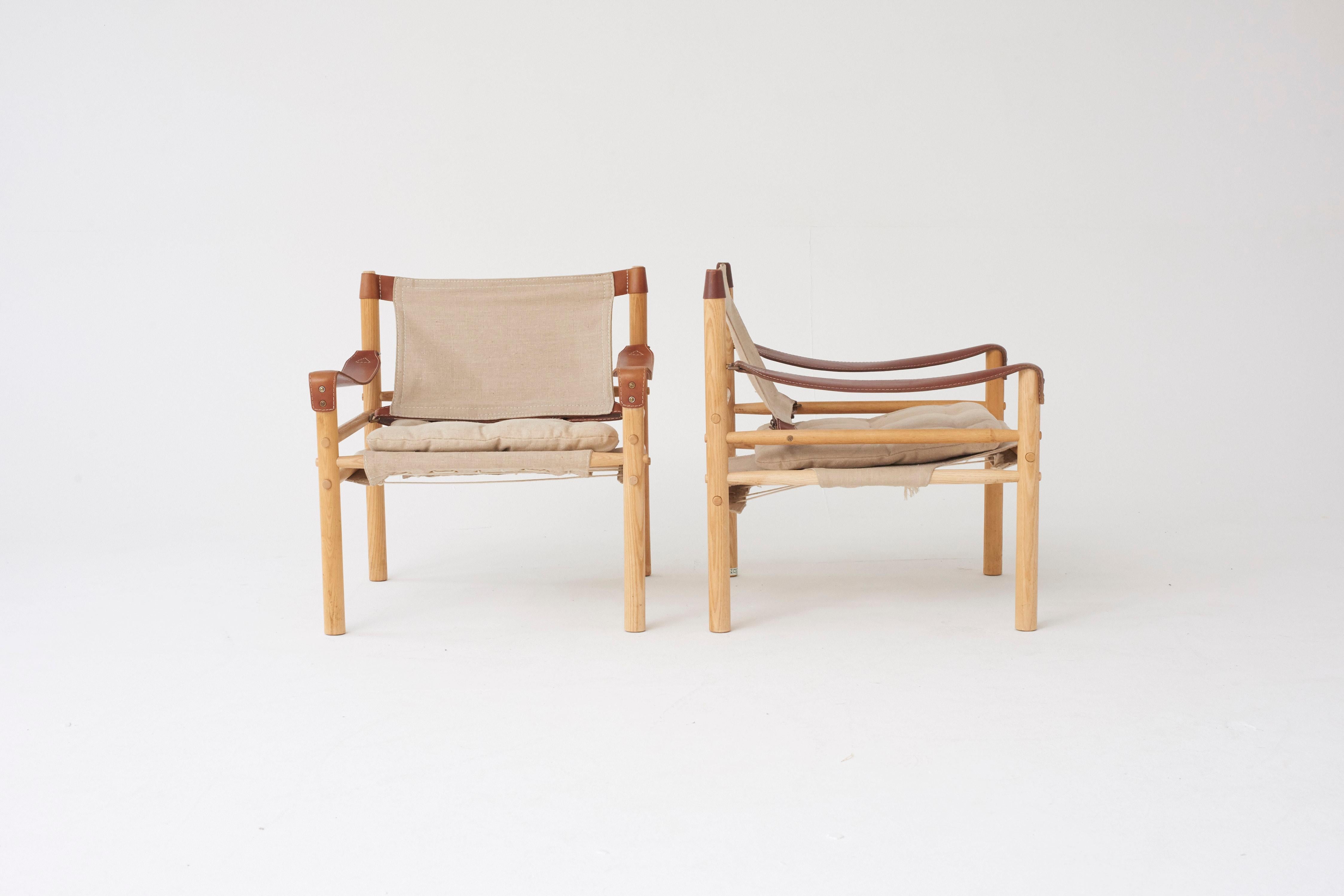 A pair of beautiful Arne Norell safari sirocco chairs in ashwood and canvas. Made by Norell Möbel AB, in Sweden with makers label intact. Very good vintage condition. Linen/canvas recently re-upholstered, slight variation in color tone between