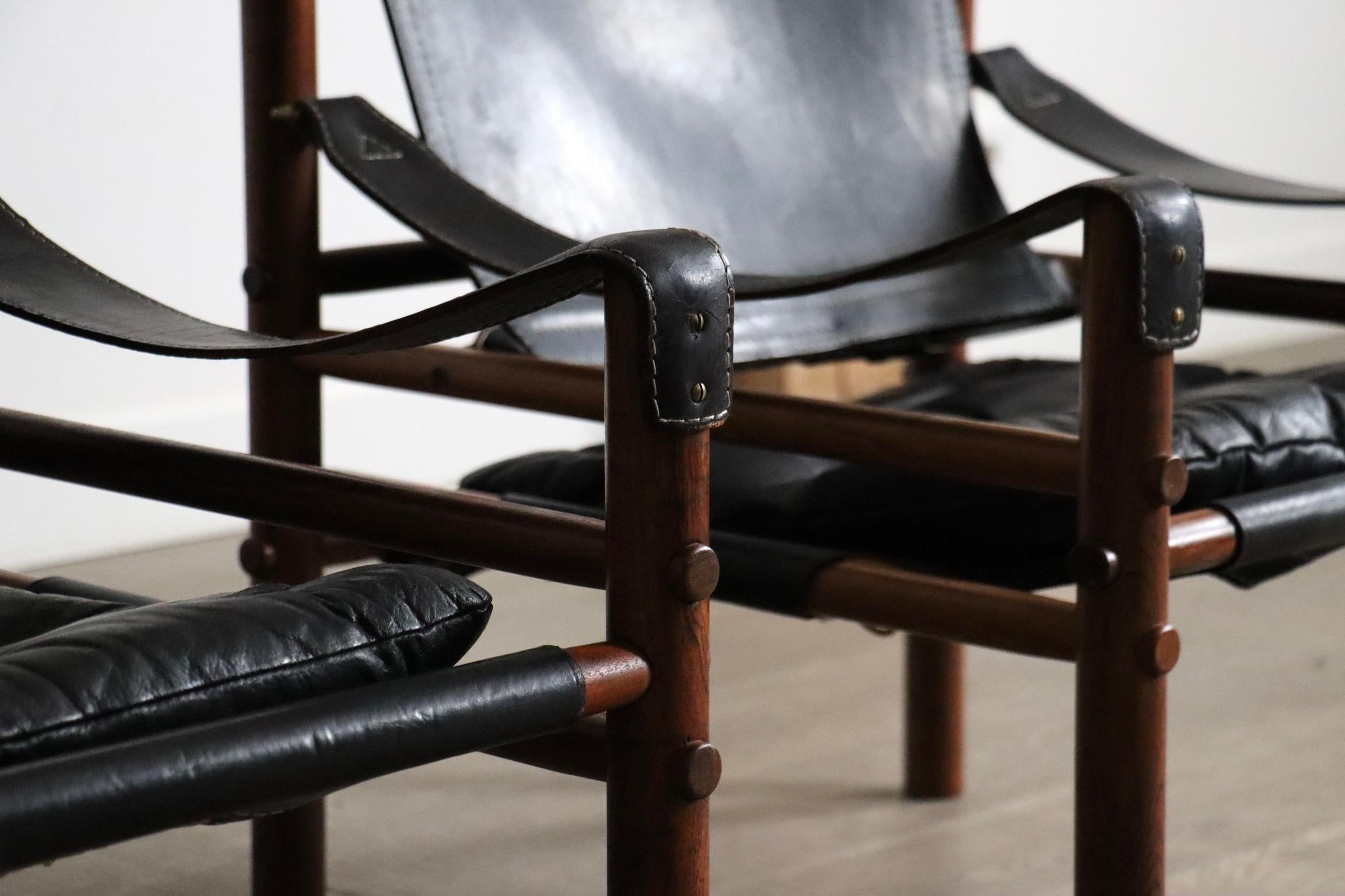 Set of 2 Arne Norell Sirocco Easy Chairs in black leather and rosewood for Norell AB, Sweden 1970s

These iconic safari chairs are made from solid rosewood frames with original black saddle leather seats, backs, and armrests, joined by brass