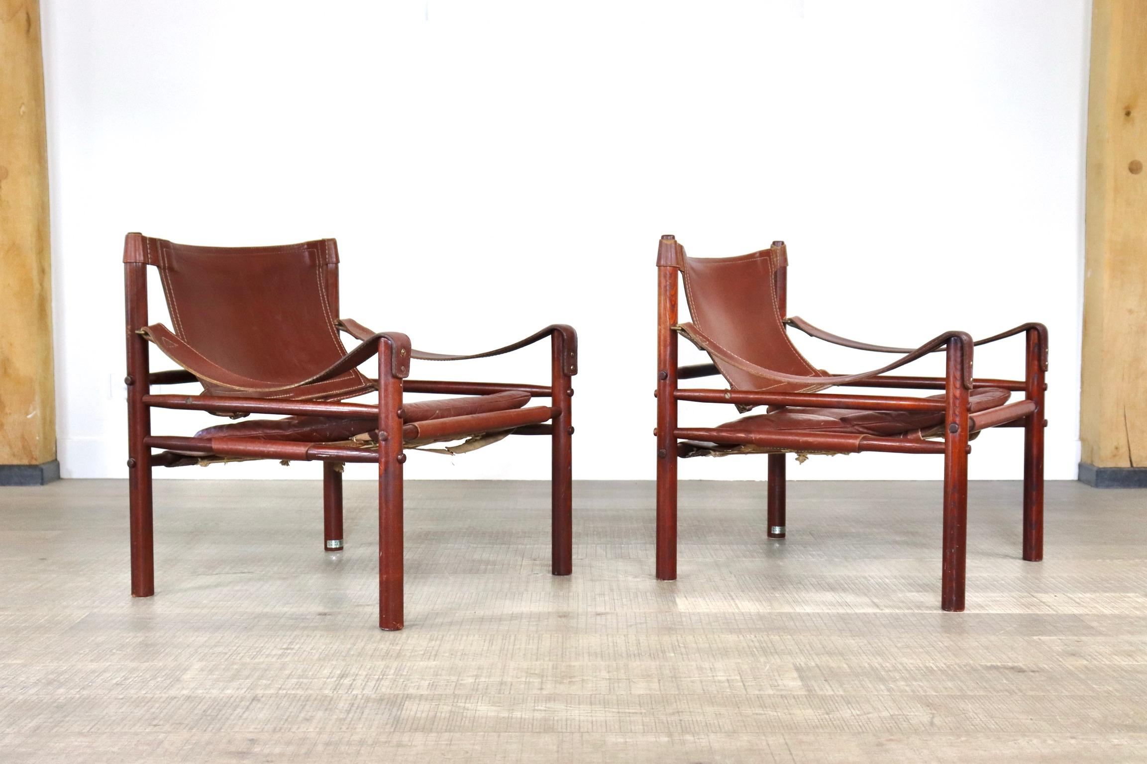 Pair of easy chairs model Sirocco in cognac leather designed by Arne Norell, Produced by Arne Norell AB in Aneby, Sweden. 
The chairs are made of a lacquered Ash wood frame and original cognac leather seating and armrests. 
Stunning design to