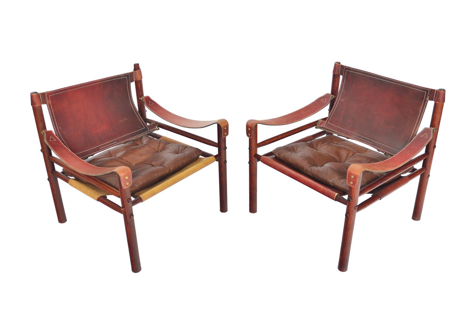 This gorgeous pair of midcentury Sirocco chairs was designed by Arne Norell in 1964. The exposed stained oak frame is constructed without any glue or screws and uses the support of slung leather. The beautiful original rust leather is perfectly
