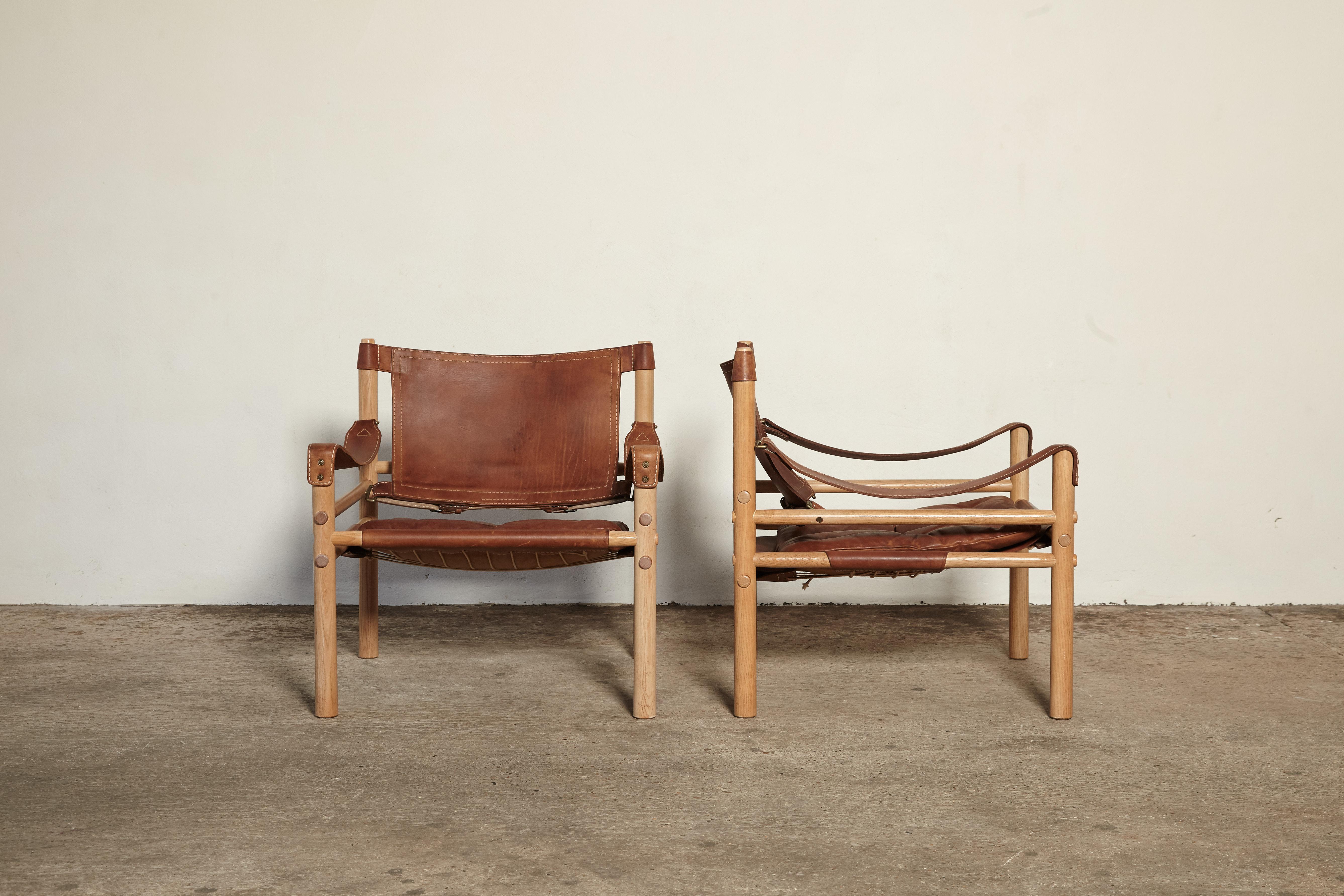 A lovely original pair of Arne Norell safari sirocco chair wtih wood frames and patinated brown leather seats. In lovely vintage condition. Made by Norell Mobel in Sweden with makers label intact. Fast and inexpensive shipping worldwide. The chairs