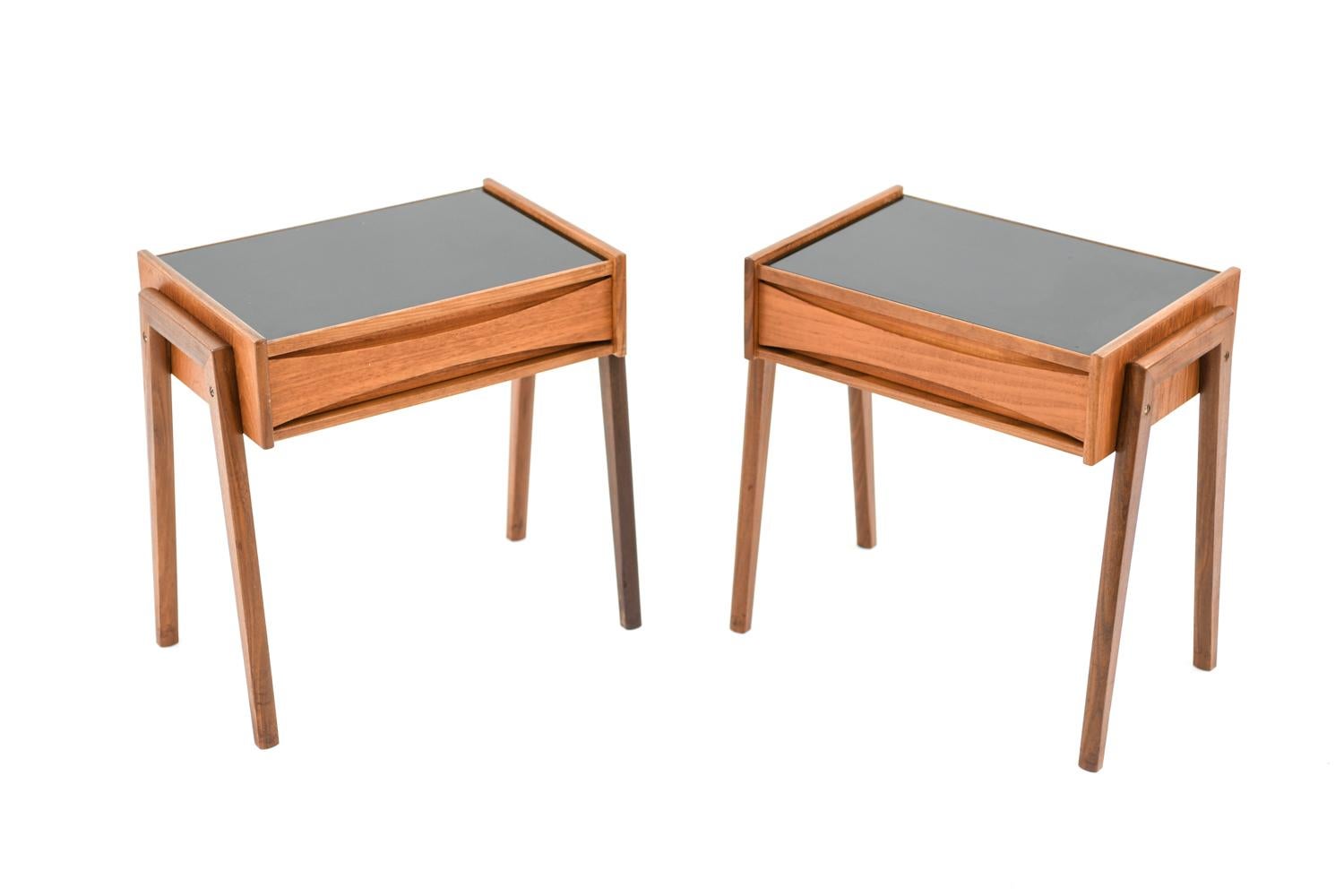 This is a charming pair of Danish midcentury side tables designed by Arne Vodder, most likely to be produced by Sibast, 1960s. These tables feature teak frames with black glass tops, giving them a sleek, modern look. The sculptured drawer front and