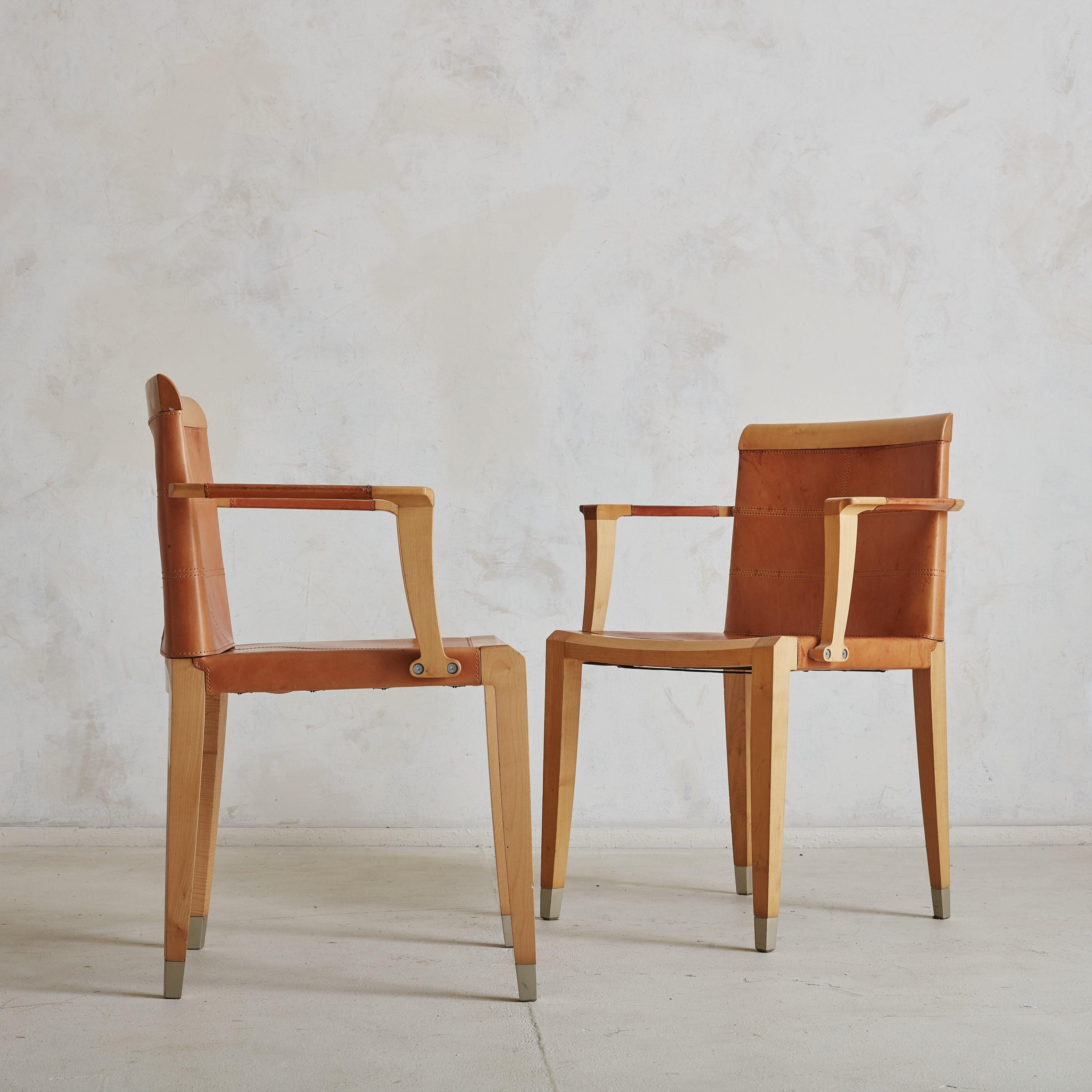 A pair of ‘Aro’ cherry wood and leather armchairs designed by Chi Wing Lo for Giorgetti in 1995. These Italian armchairs feature angular solid cherry wood frames in a warm, blonde hue with subtly tapered legs and metal capped feet. The seats, backs,