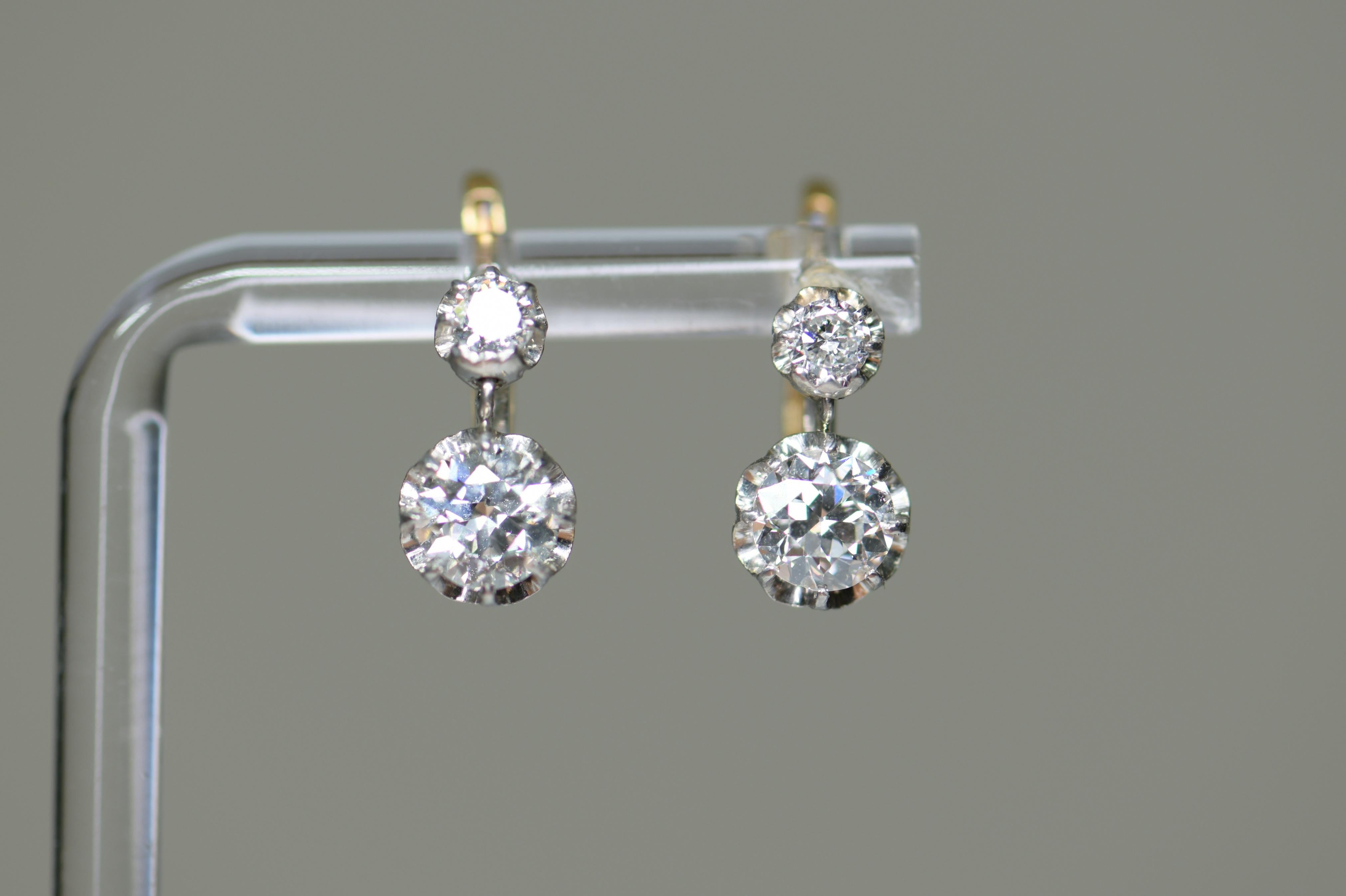 A very bright and well-matched pair of diamond earrings made circa 1920.  These earrings feature both two old European set in platinum over 18K yellow gold with a front clasping hinge. The diamonds drop just below the ear, suitable for both day and