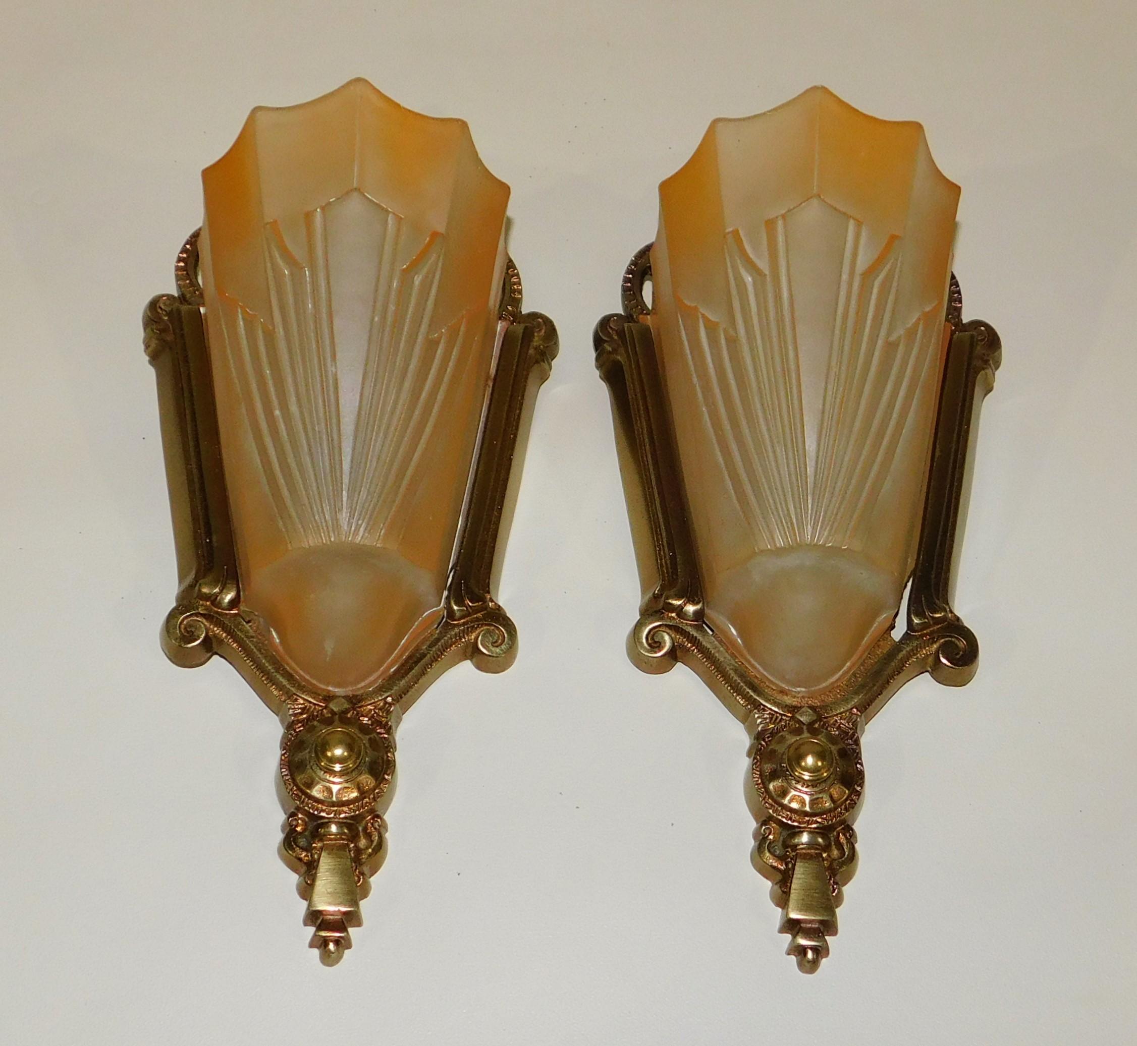 Beautiful pair of Art Deco brass wall sconces with original peach colored glass slip shades, restored and rewired, circa 1925-1930.