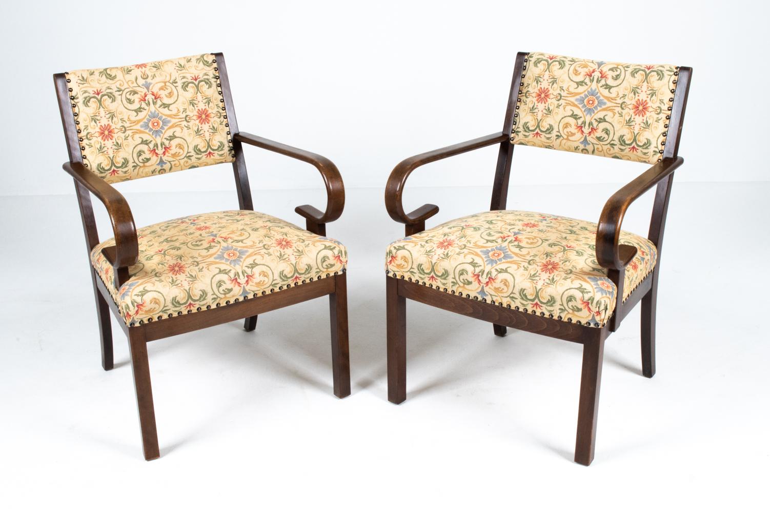 Dating from the Late Art Deco period, this extremely rare and unusual pair of armchairs features dramatic hairpin arms and simple rectangular backs. The frame is solid beechwood, finished in a rich mahogany stain. Woven floral fabric and nailhead
