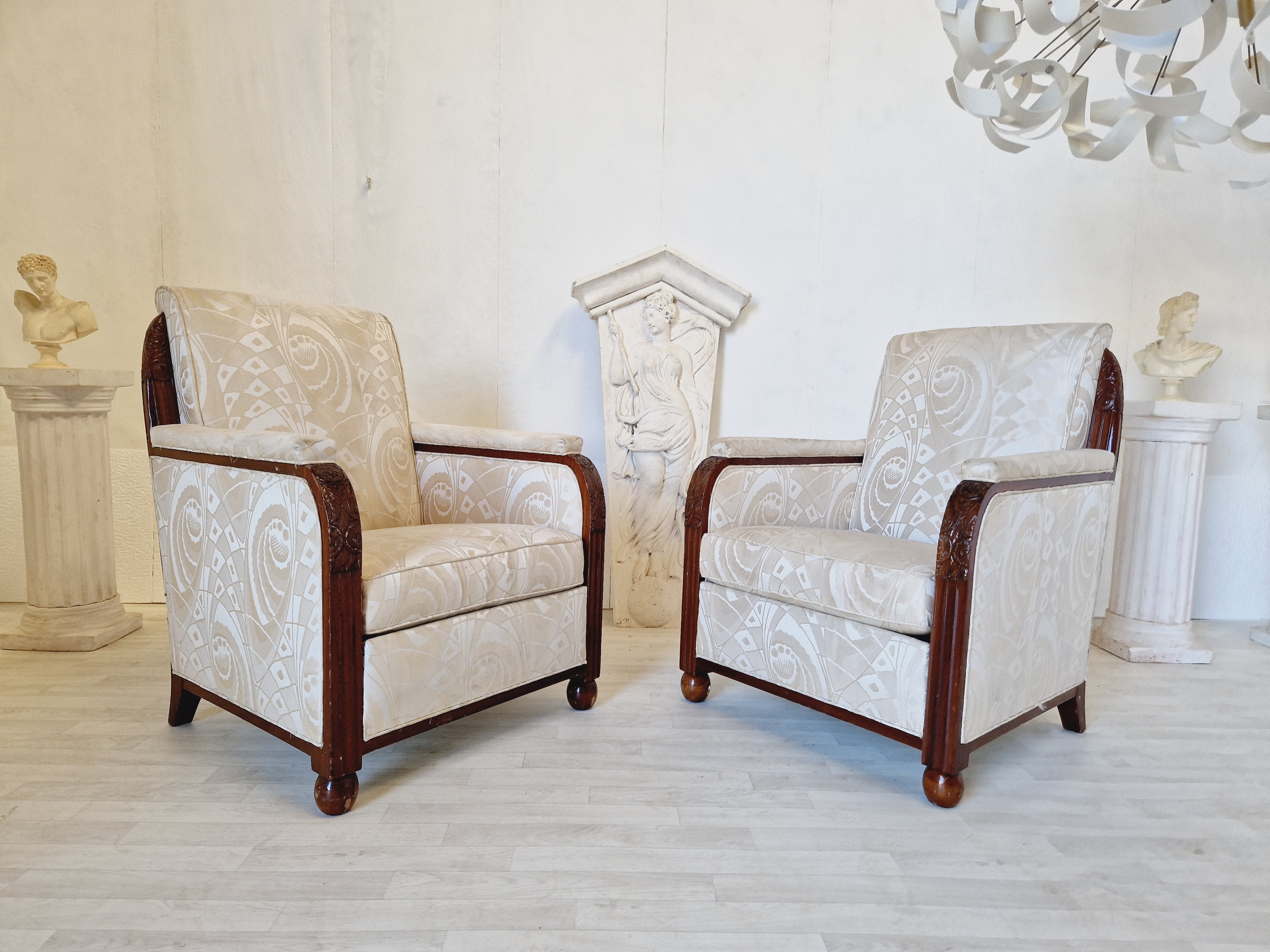 This pair of vintage Art Deco Armchairs are from the 1930s and feature a beautiful cube style design with a white colour upholstery and walnut frame. This set includes two chairs made of walnut and upholstered with satin synthetic type fabric. The