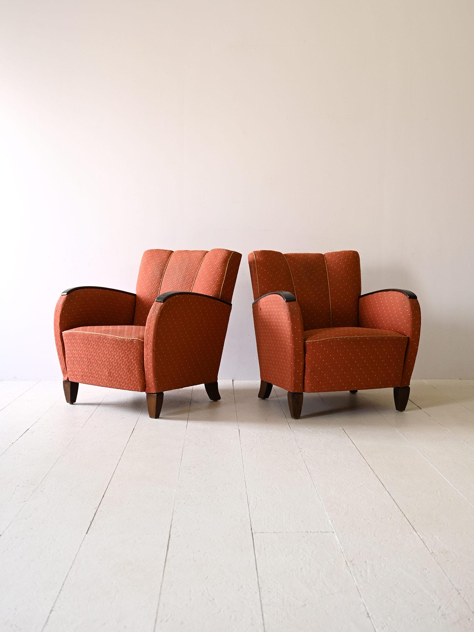 Paire de fauteuils déco originaux des années 1930.

Les fauteuils se distinguent par leurs accoudoirs en bois teinté, dont la teinte grise s'harmonise à merveille avec le tissu d'époque. Les surpiqûres rouges ajoutent une touche vivante et créent un