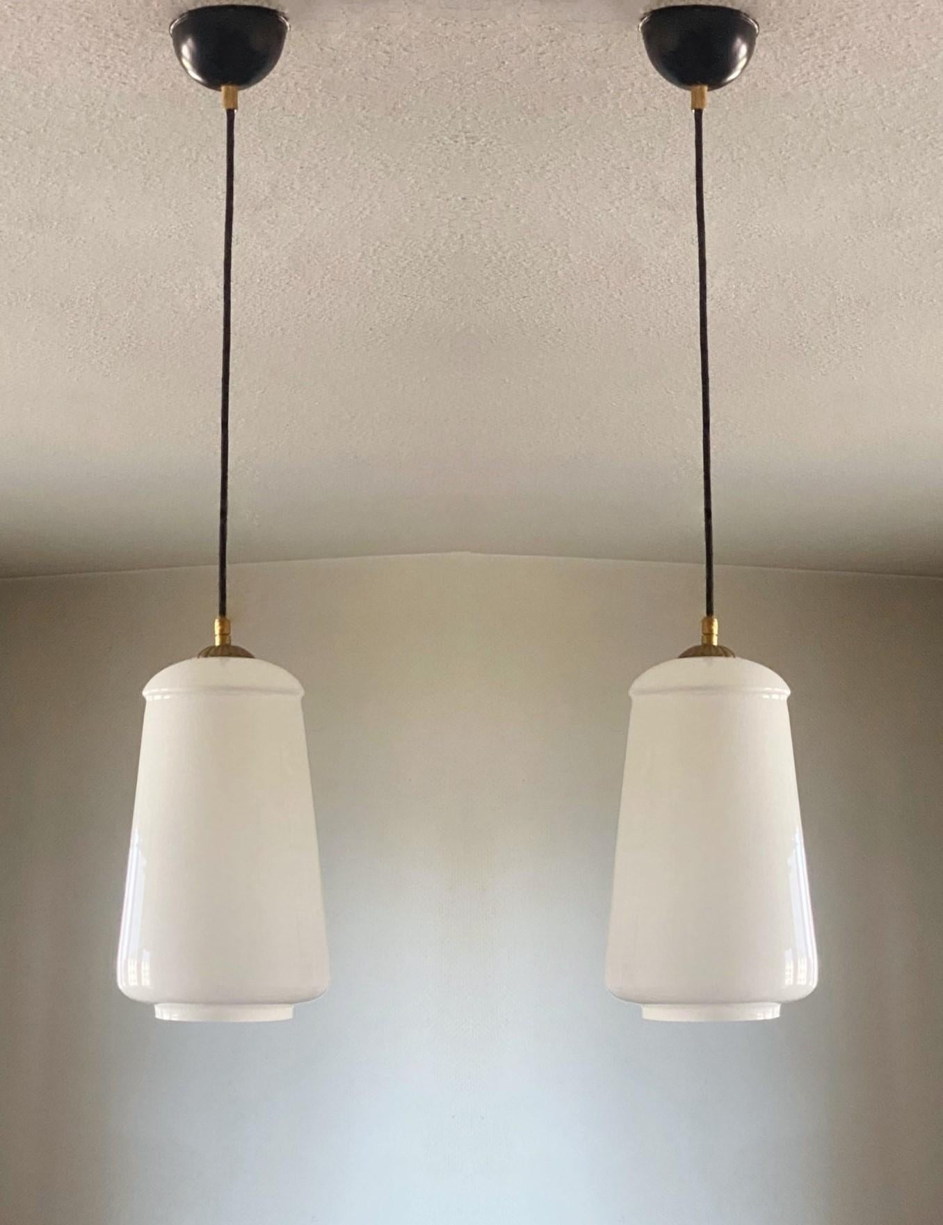 Ein Paar Bauhaus-Opalglas-Anhänger, Deutschland, 1930-1939. Konisch geformter Opalglasschirm, Messing montiert, beide Stücke in sehr gutem Zustand.
Tatsächliche Höhe 30