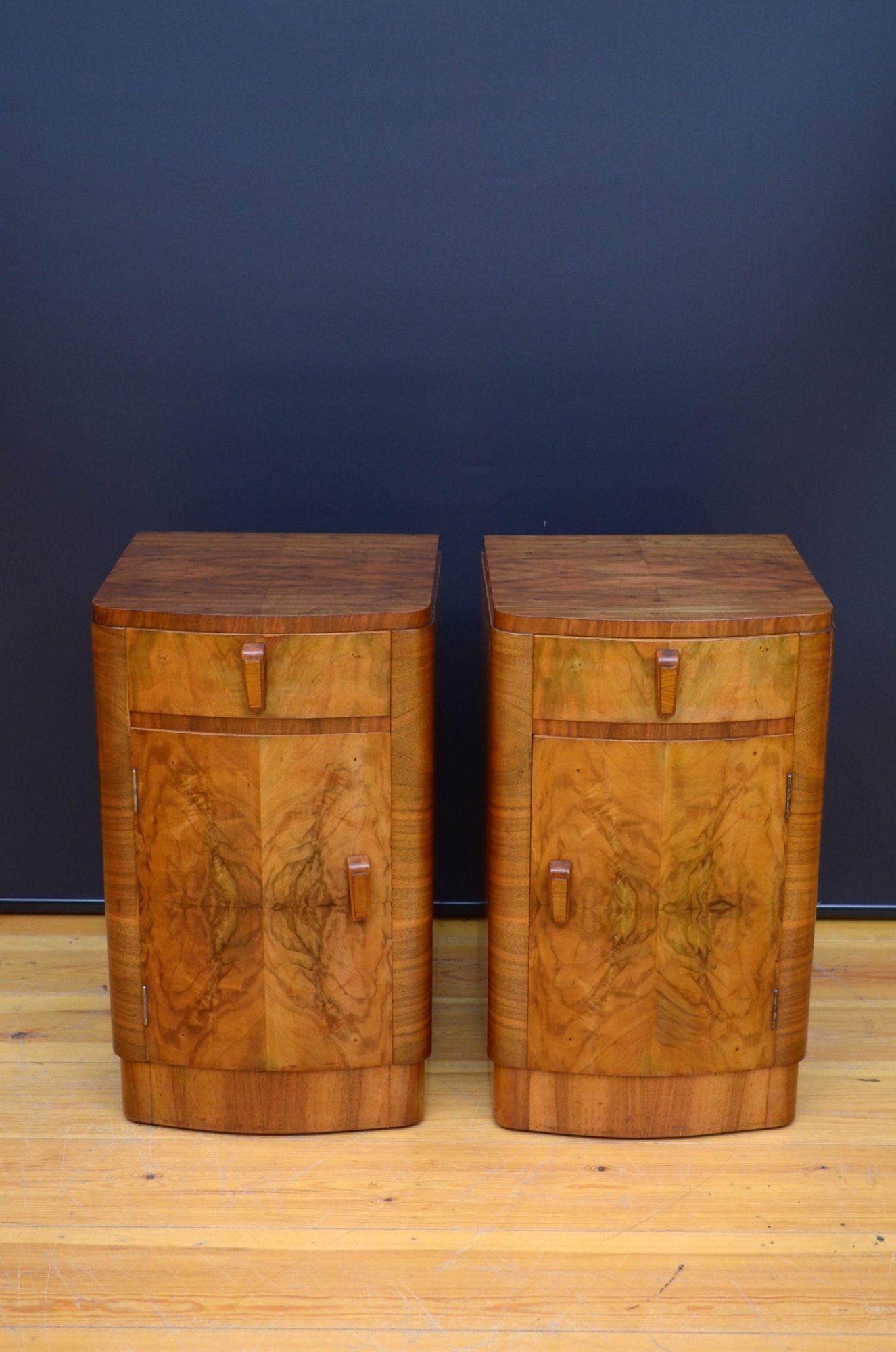 Sn5469 Pair of Art Deco walnut bedside cupboard of bow fronted design, each having figured walnut top above a drawer and cupboard door, all fitted with original handles and standing on plinth base. This antique pair of bedside cabinets is in home