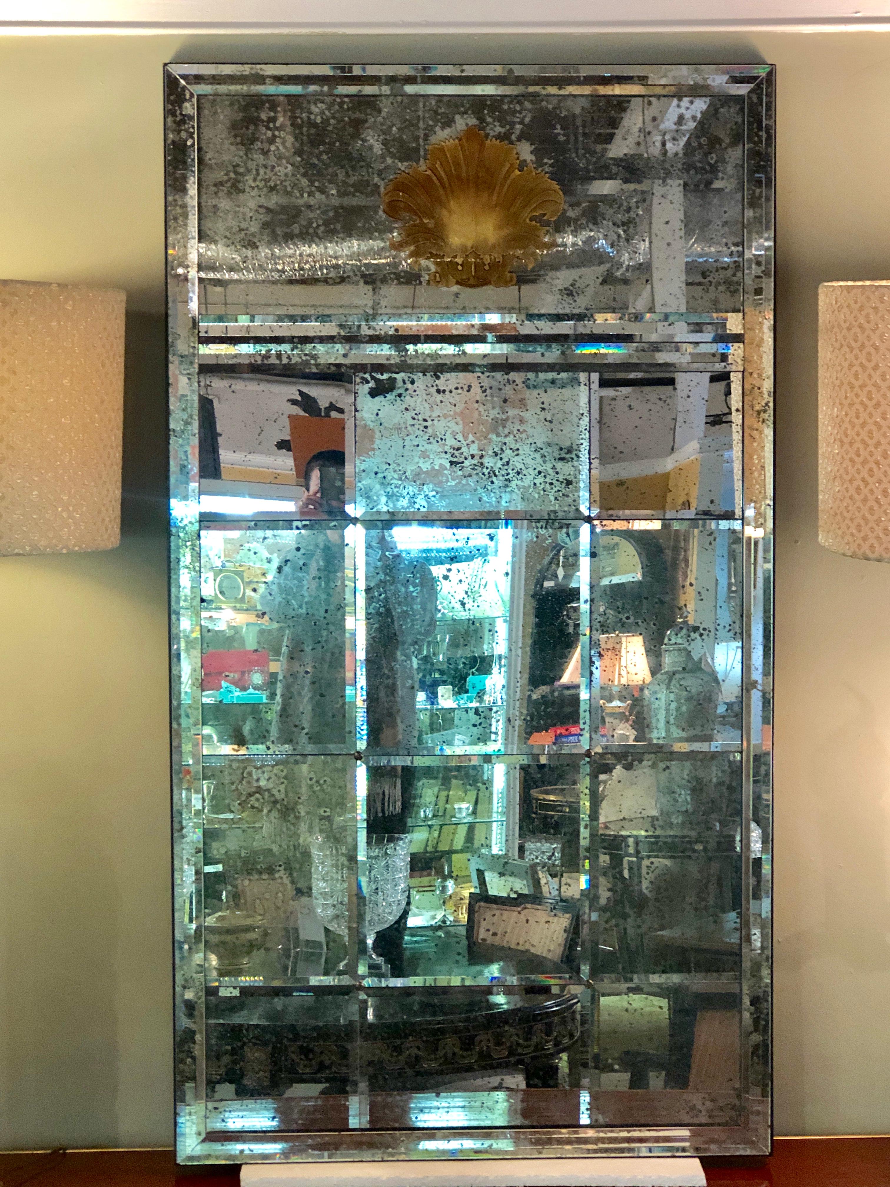 Pair of Art Deco beveled console or wall mirrors with gilt engraved shell motif. These one of a kind spectacular mirrors have a dozen beveled antiqued mirror glass panels under a finely carved and engraved glit gold motif. The entire mirror is set