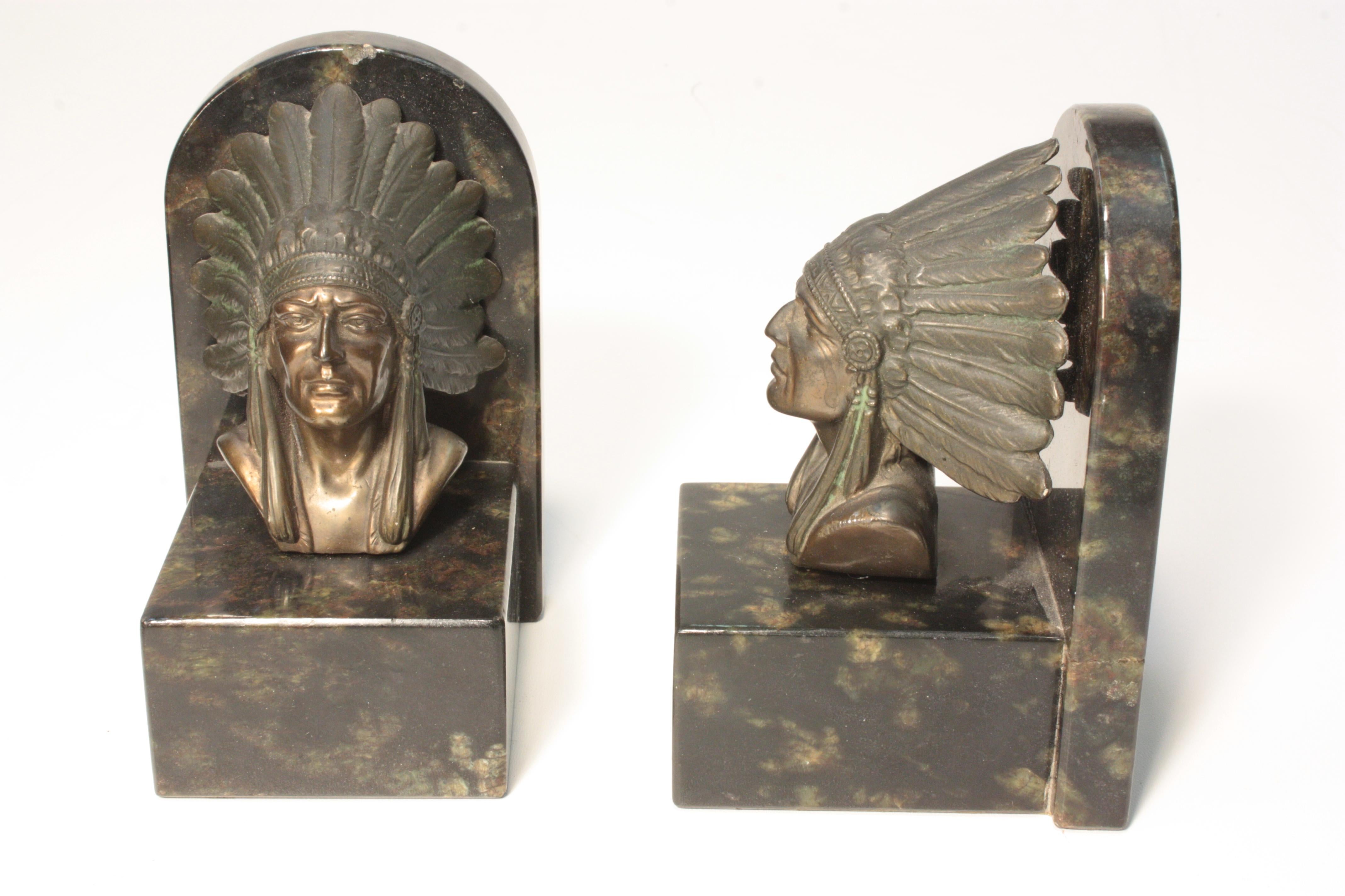 Each attractive black and striated base is mounted with a bronze bust of a Chieftain in feathered bonnet.