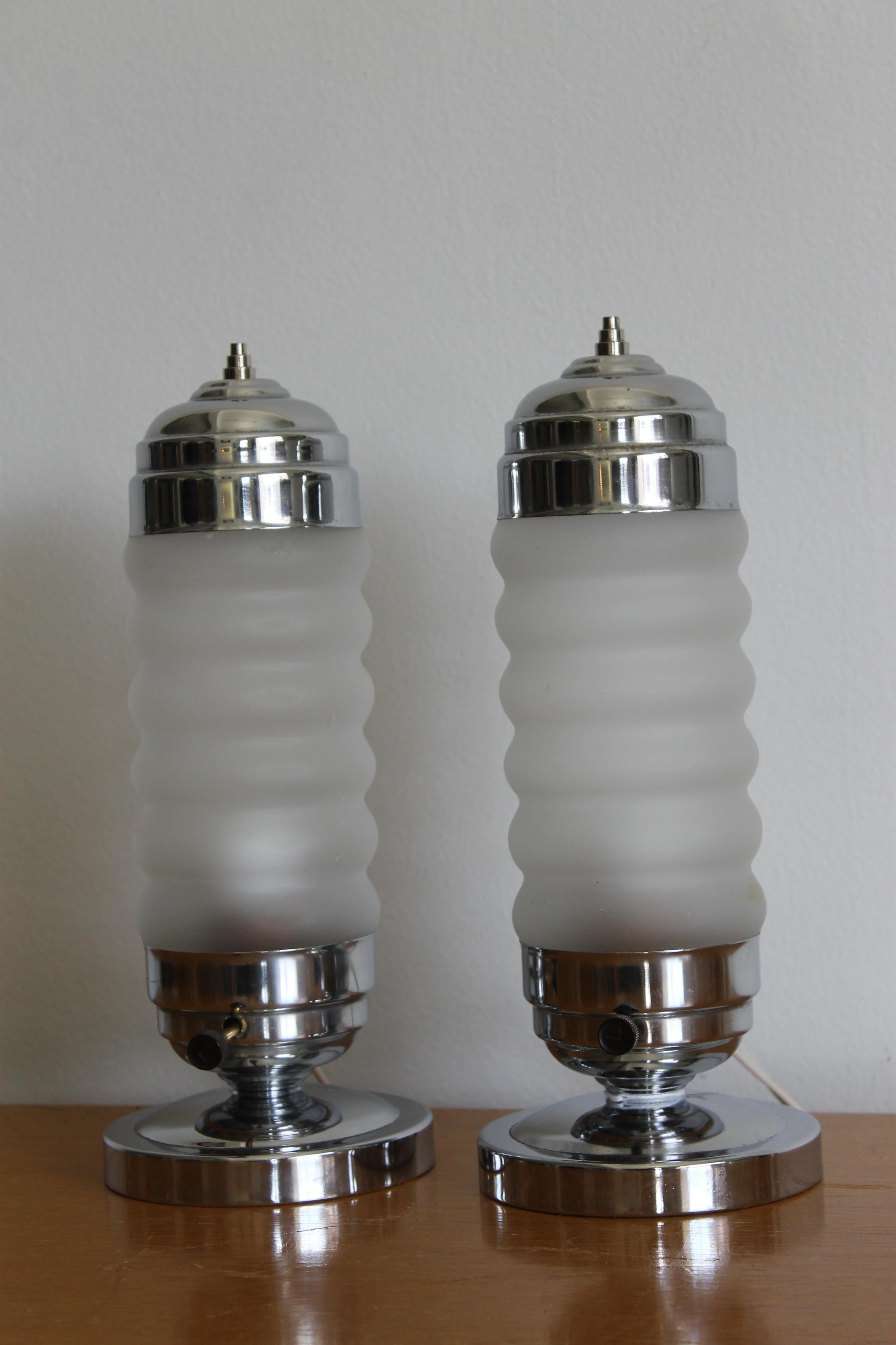 A pair of streamlined chrome and frosted glass dresser lamps. These are 11