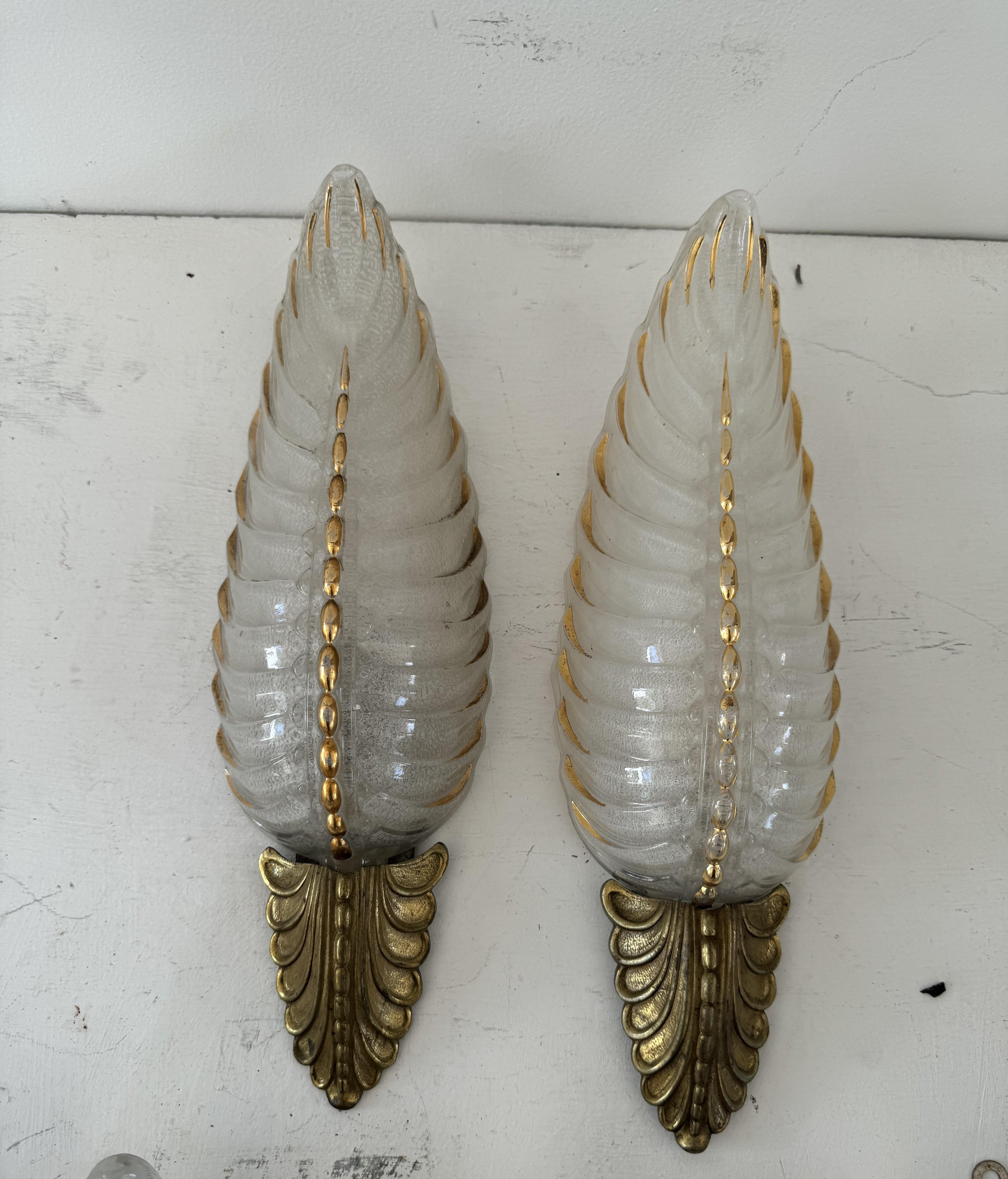 Coppia di appliques Art Deco in vetro pressato e ottone prodotte da Ezan in Francia intorno agli anni '40, con un bellissimo disegno di palme sulla ferramenta.
Can presenta leggere variazioni di patinatura che possono essere facilmente lucidate.
