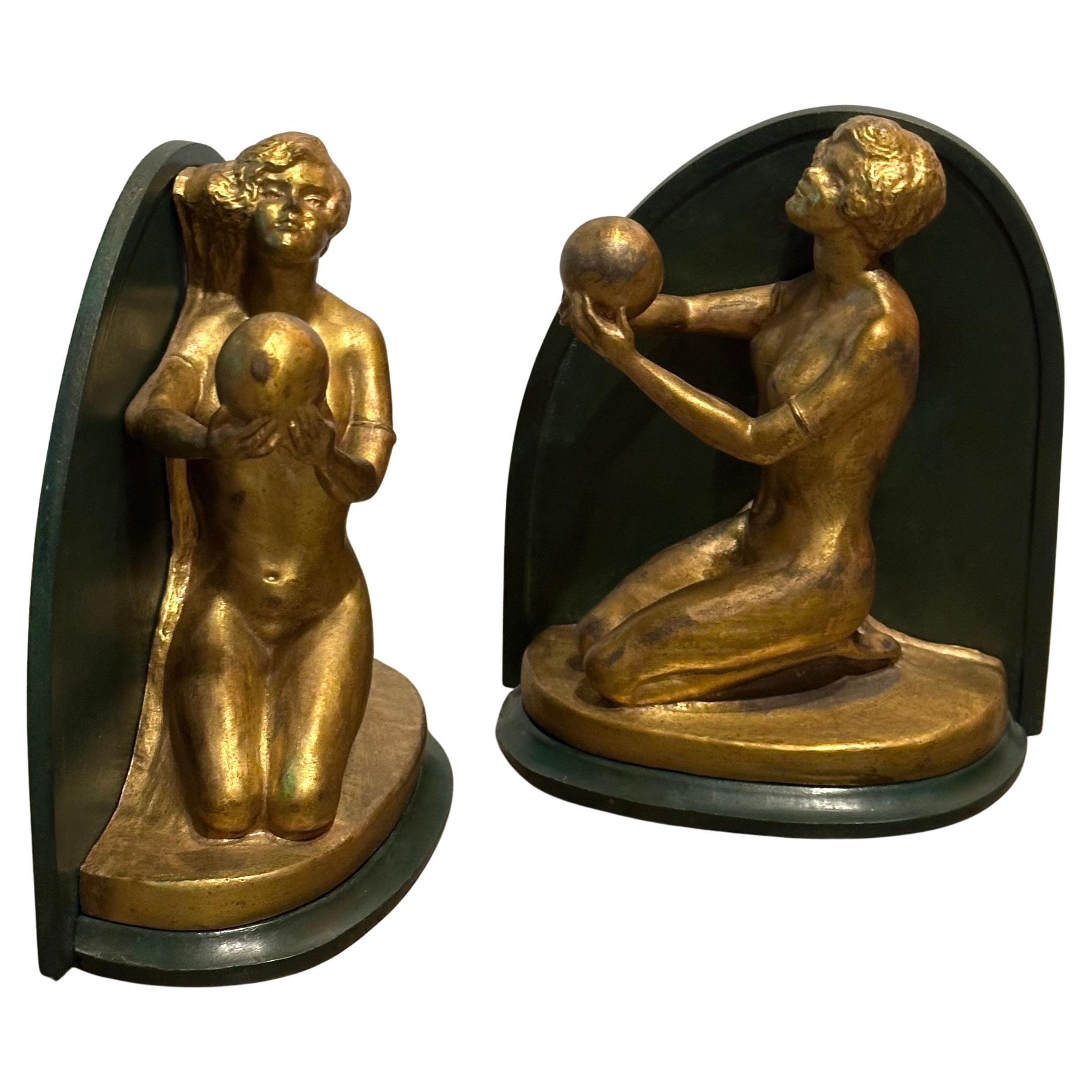 Coppia di fermalibri in ottone e metallo con nudo di donna e sfera in stile art deco, circa 1930. Una splendida donna nuda in ottone, spesso descritta come una ragazza flapper con un taglio di capelli a caschetto, siede su una solida piattaforma di