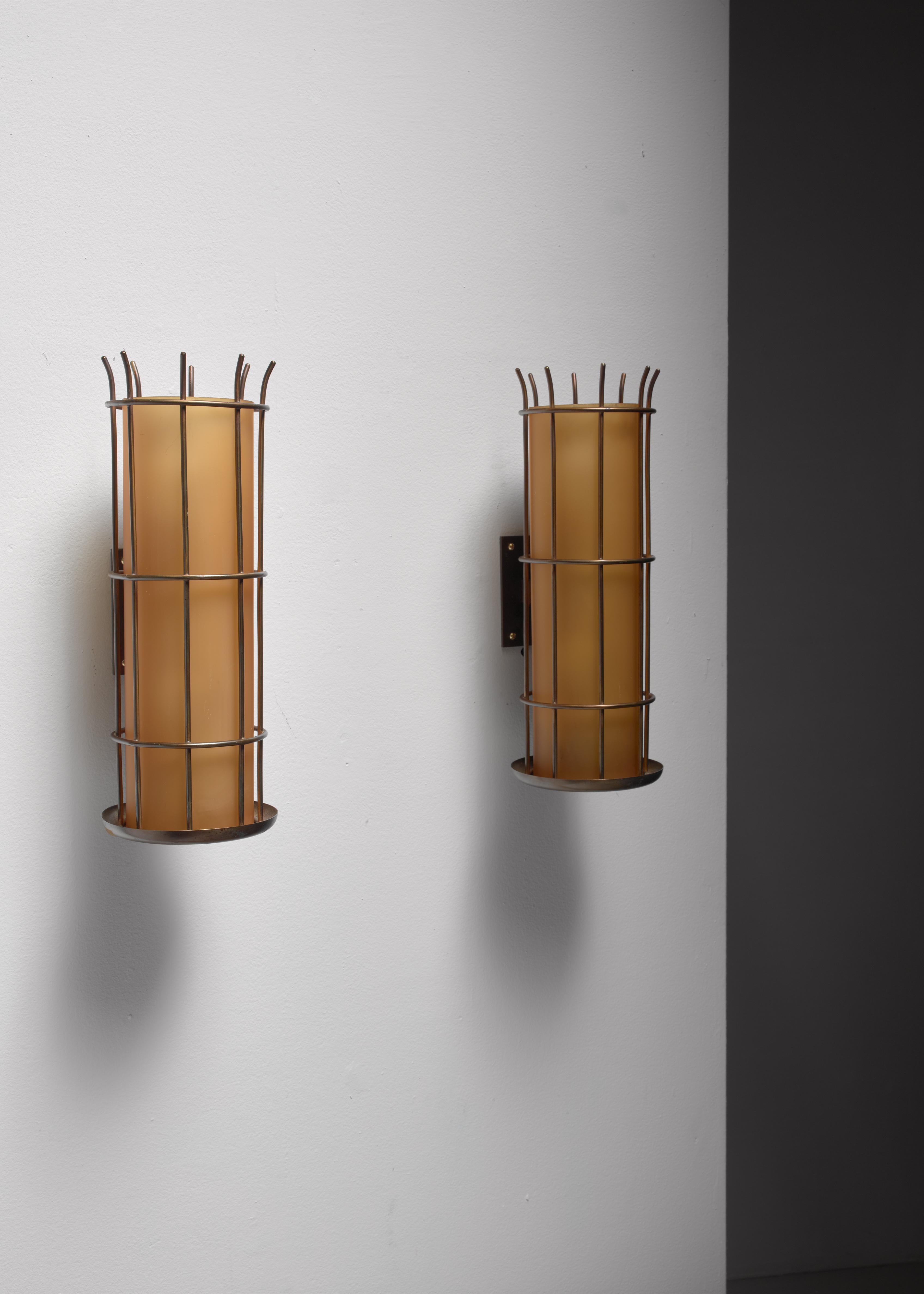 A pair of Art Deco wall lamps, made of yellow glass diffusers in a round brass frame.
