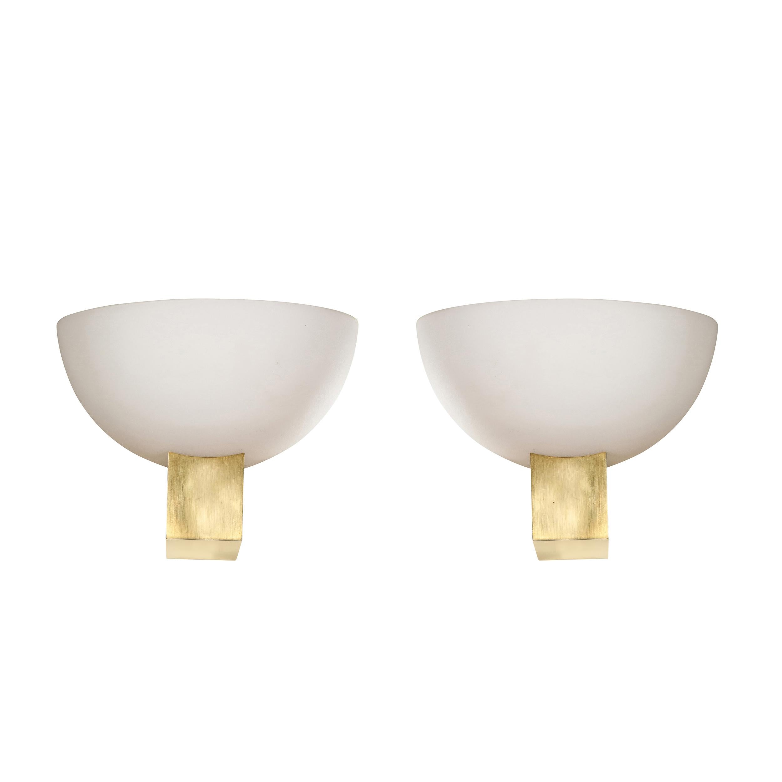 This refined pair of Art Deco brass and frosted glass reverse dome sconces were realized by the esteemed atelier of Jean Perzel in France circa 1940. They feature volumetric rectangular bodies in brass that dramatically cantilever out from the wall.