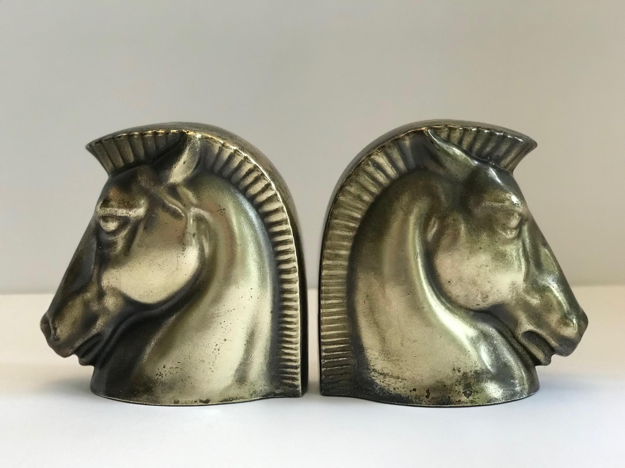 Pair of stunning Art Deco Trojan horse head bookends. Brass plated over hand cast metal. The bookends exhibit a good amount of patina appropriate for their age, adding to their beauty and character. Machine Age design and highly stylized from all