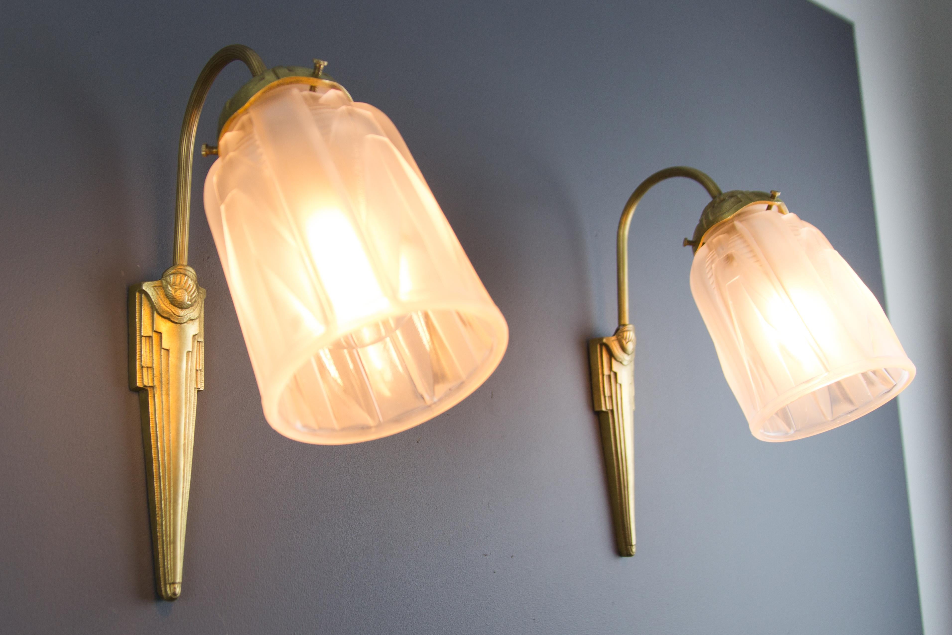 Elegant pair of French Art Deco wall sconces with frosted white glass shades with geometrical Art Deco style elements, signed Muller Frères Luneville. Beautiful bronze frames are numbered and have marks C.R., attributed to Charles Ranc.
Each sconce